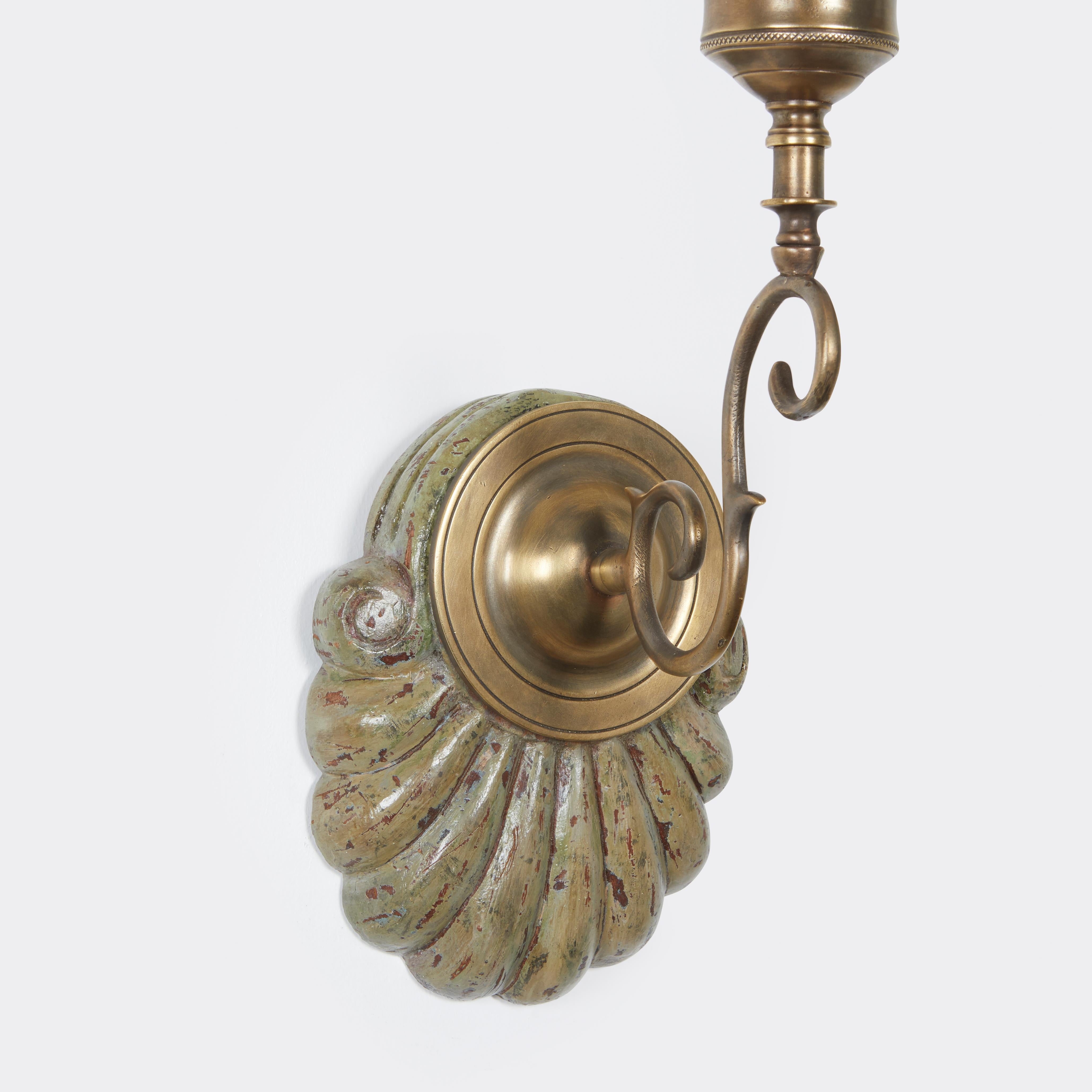 A pair of hand-carved mahogany shell form Georgian-style backplates with a green craquelure painted surface, brass sconce fittings and clear hurricane shades. Sconce is measured from bottom of backplate to top of shade height 23