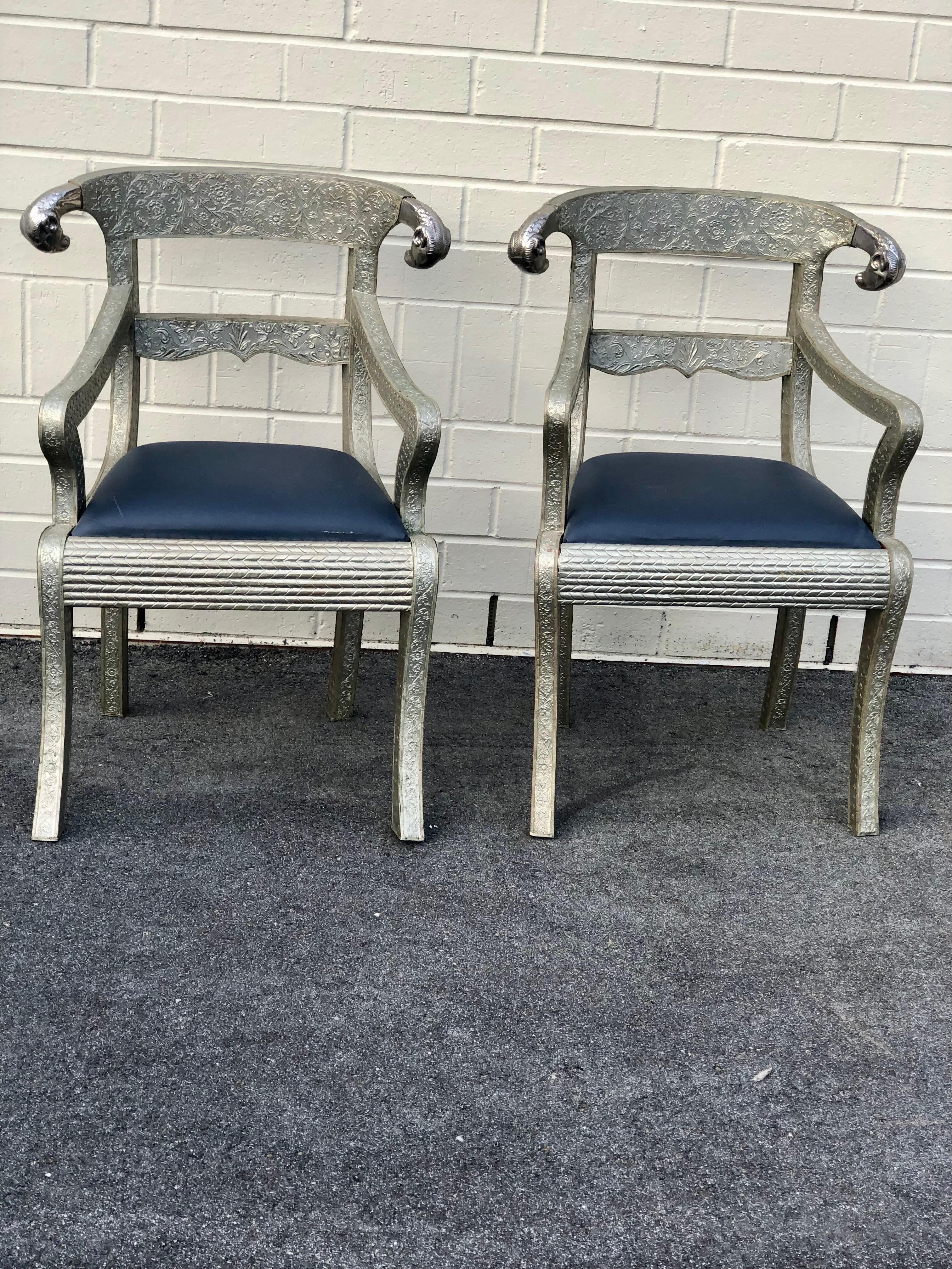 A magnificent and striking pair of Anglo Indian armchairs adorned with intricate silver metal cladding and embellished with captivating Rams Heads motifs. These armchairs seamlessly blend the opulent essence of British colonial design with the
