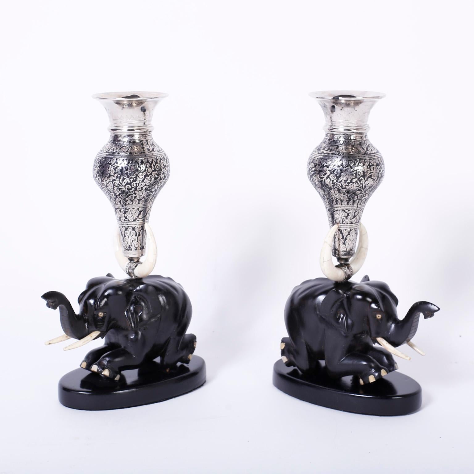 Fanciful antique Anglo-Indian vases with silver metal vessels hand tooled with floral designs mounted on carved ebony kneeling elephants enhanced with bone details.