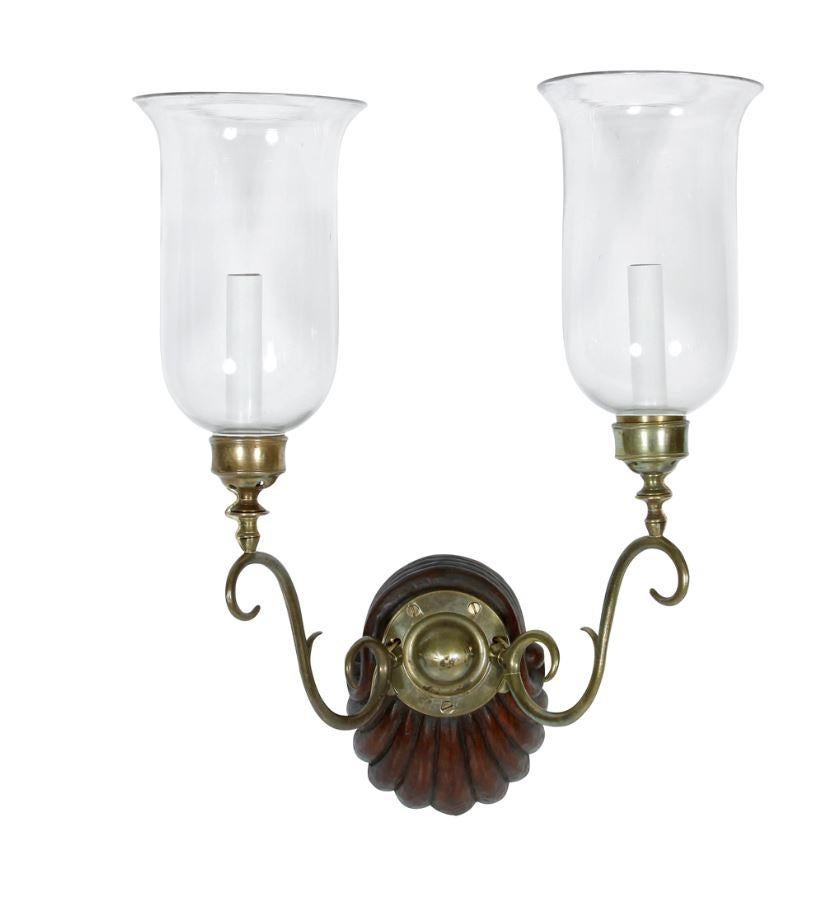 Pair of Anglo-Indian two-light hurricane sconces with wood shell motif base and scrolled brass arms.