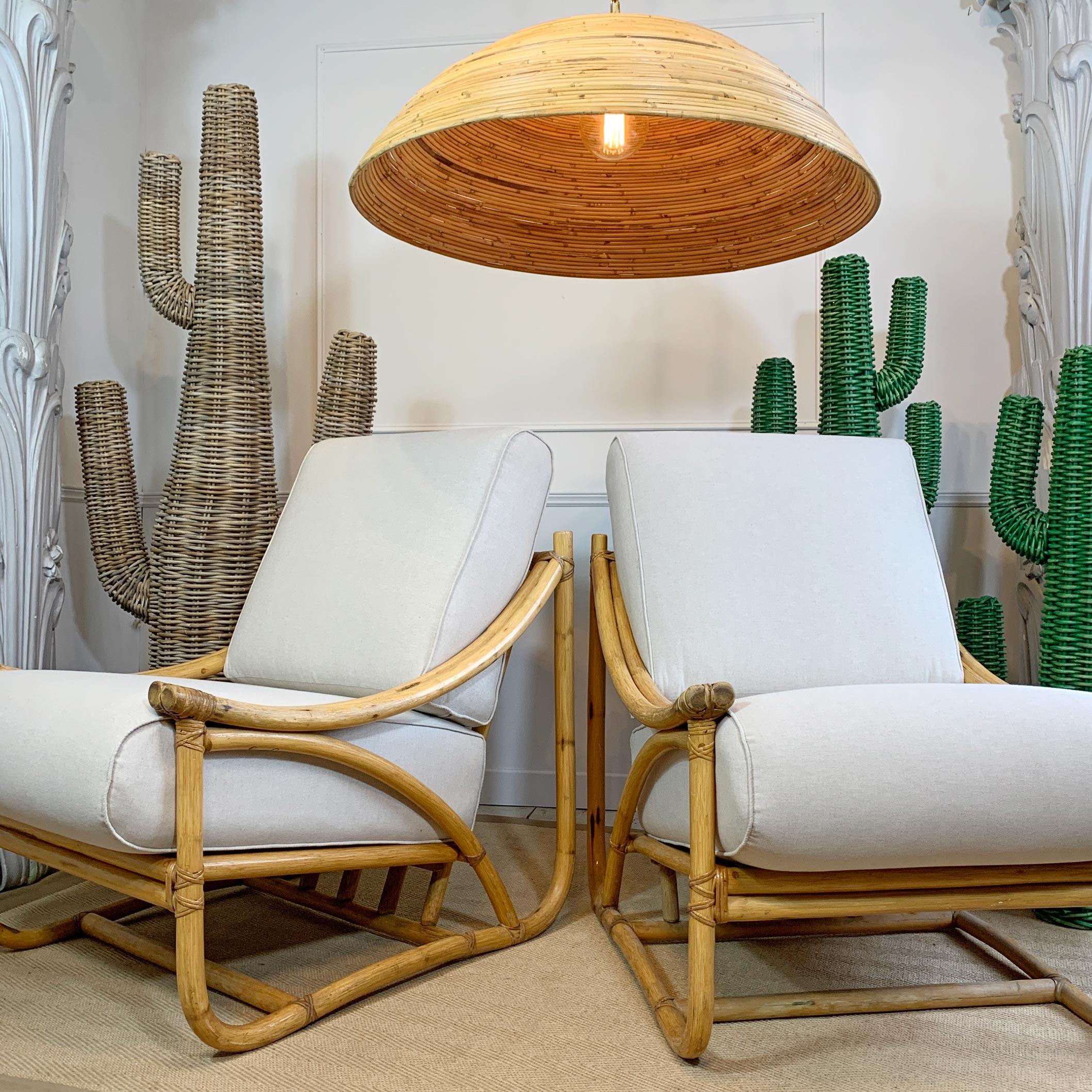 Superb pair of 1950s rattan lounge chairs by Angraves of Leicester, from their Invincible collection, each chair with the Angraves identification plaque. The seat cushions have been fully professionally reupholstered in oatmeal linen fabric.

In