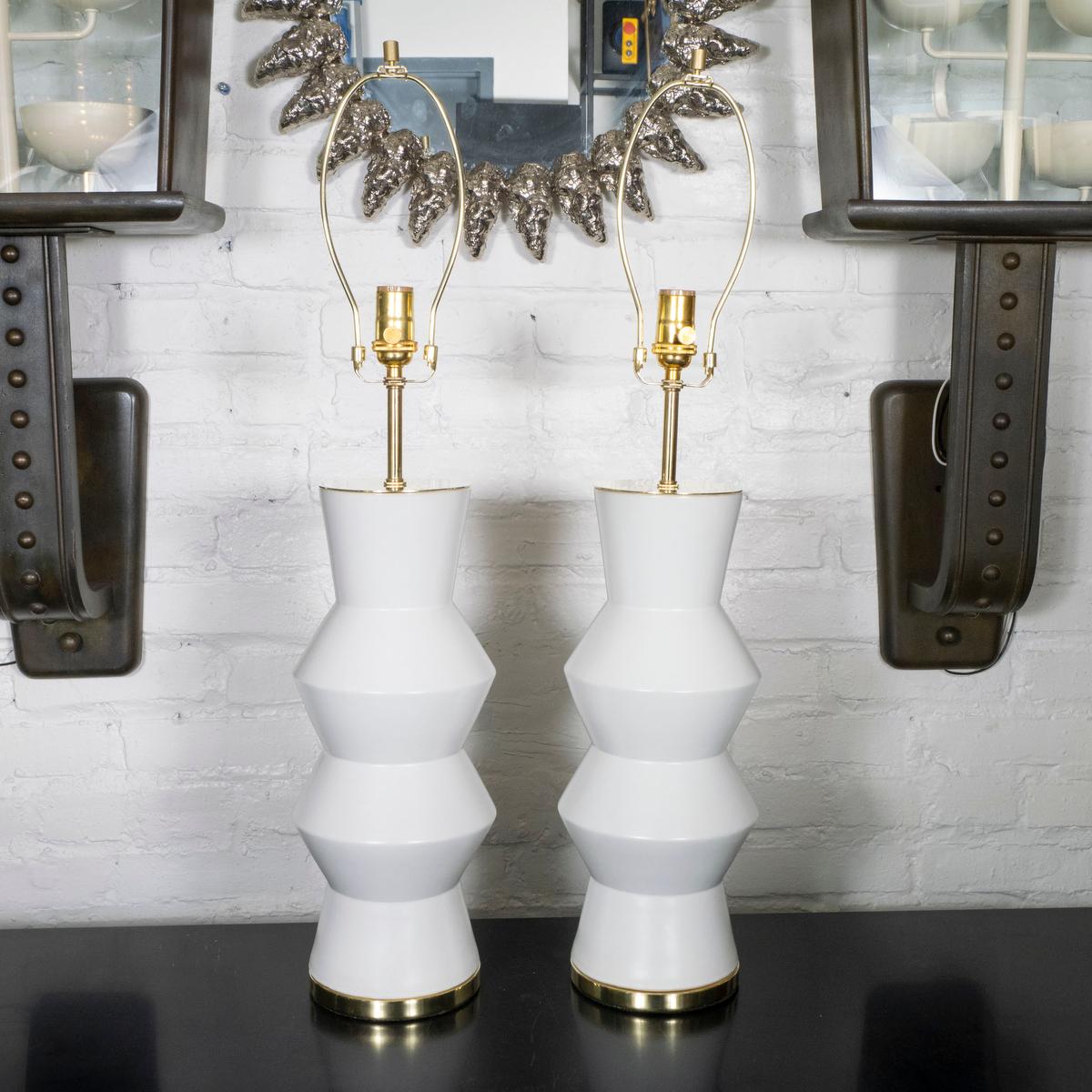 Pair of angular white ceramic table lamps with brass hardware.