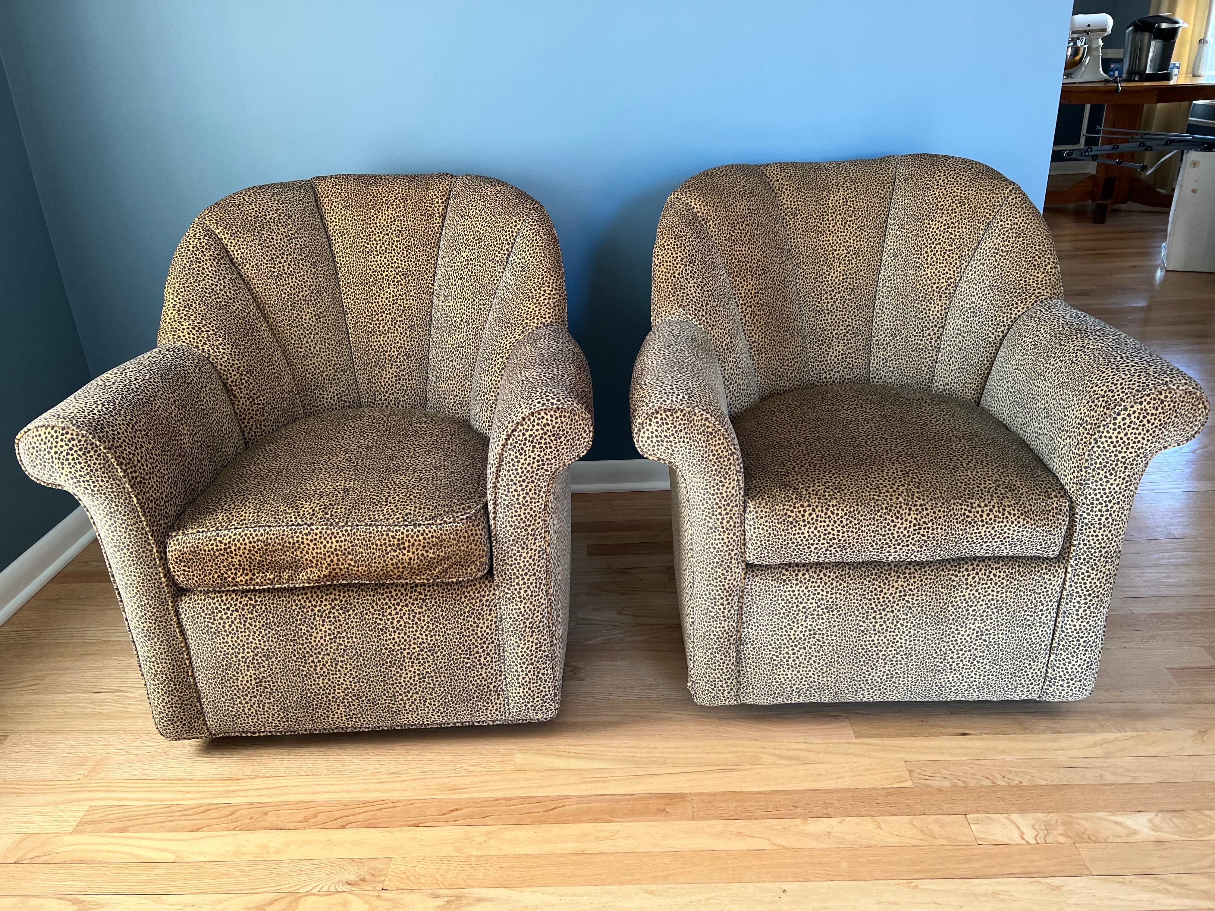 Pair of Animal Print Swivel Chairs. Hollywood Regency style channel back swivel arm chairs in animal print upholstery. Soft chenille fabric. One seat cushion has piping and one does not, however we have extra throw pillows to create the piping for