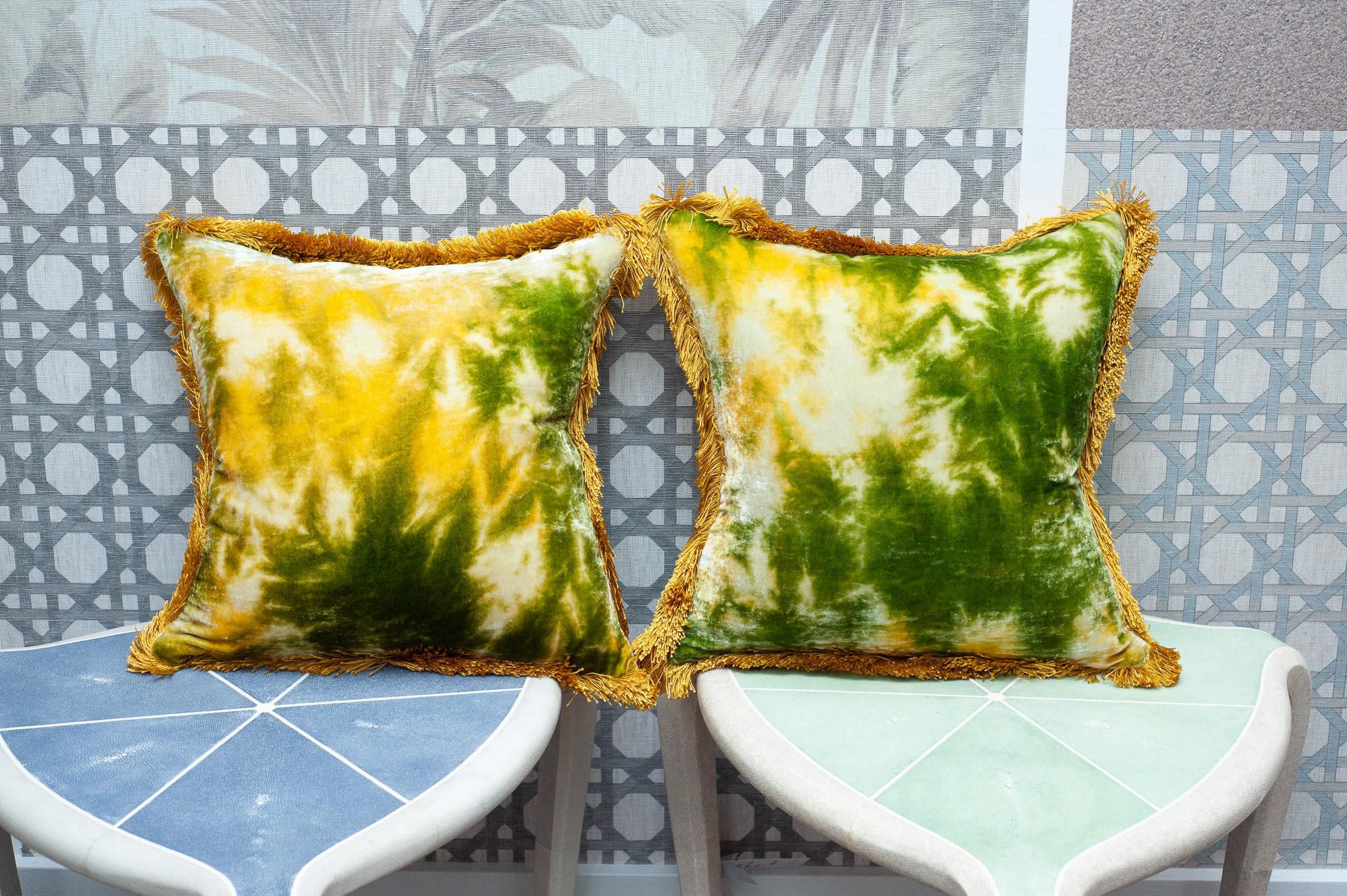 A pair of green and gold silk velvet cushions from Anke Dreschel featuring fringe border, square shape and concealed rear zip fastening. Filled with 100% Canadian feather and down.