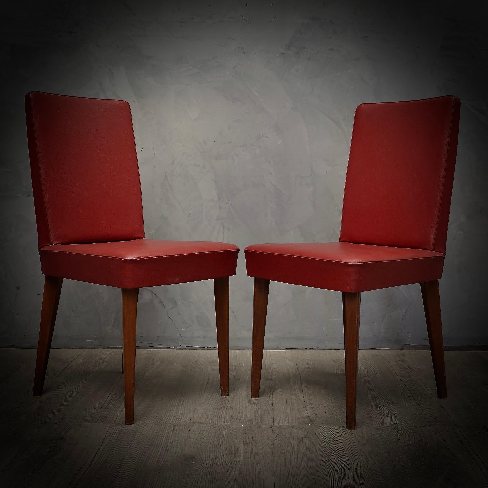 Paire de chaises raffinées d'Anonima Castelli, d'une belle couleur rouge vif. Raffinement et classe comme le style de la maison.

Structure en bois, recouverte de cuir écologique rouge, original de l'époque. Quatre pieds en bois de chêne laqué.