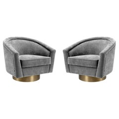 Coppia di poltrone in tessuto grigio antracite con base girevole in oro opaco.