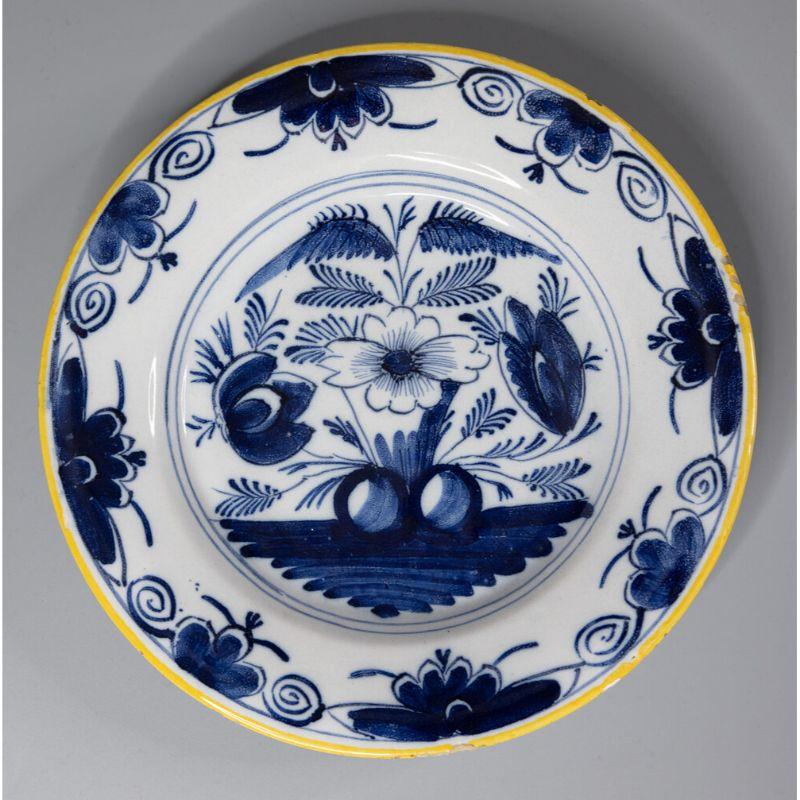 A gorgeous pair of antique 18th-century Dutch Delft faience plates. These lovely plates have a hand painted floral design in vibrant cobalt blue and white with bright yellow rims. They would look fabulous displayed on a wall or shelf in any room.

