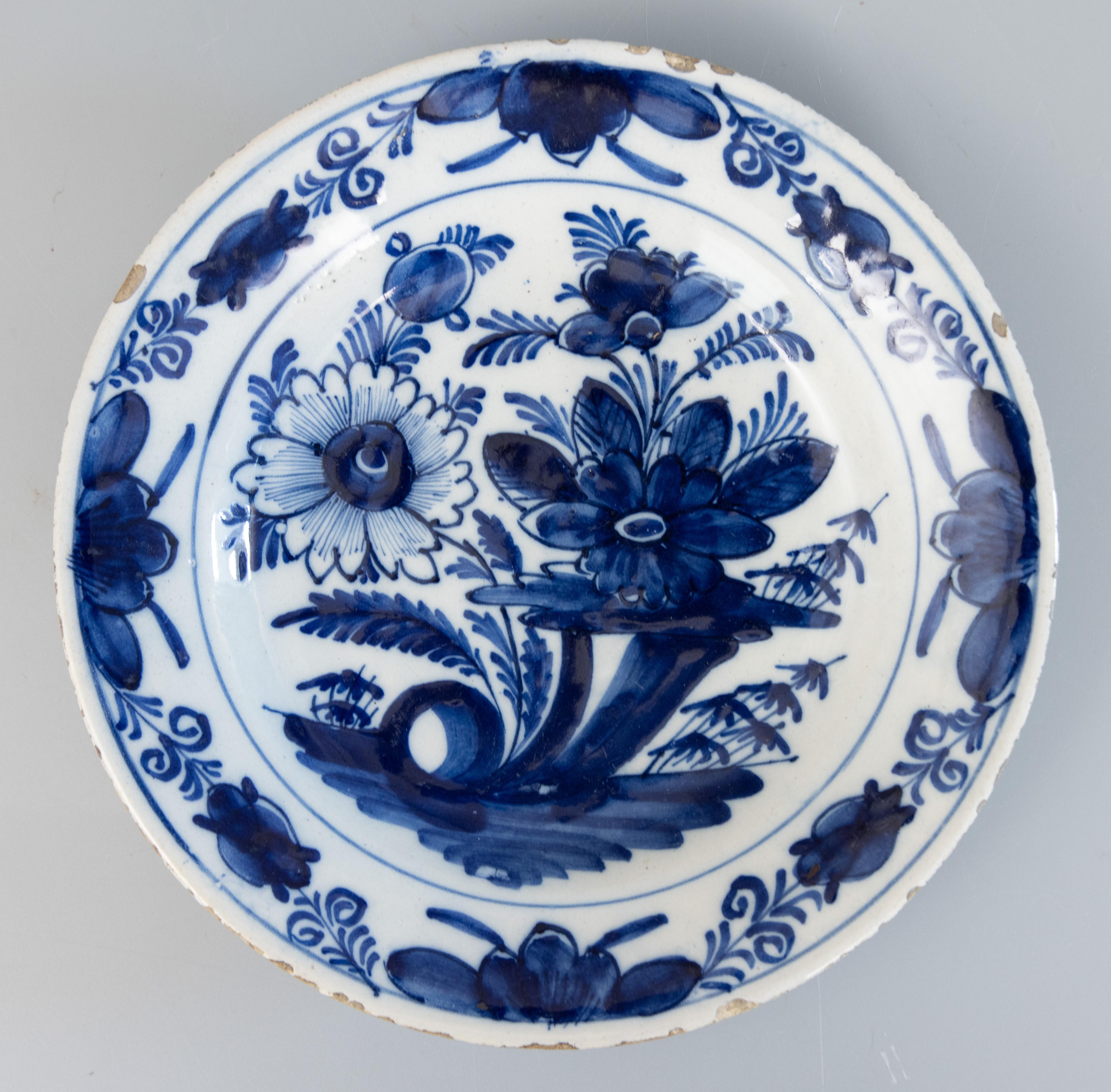 A gorgeous pair of antique 18th-Century Dutch Delft faience flower garden plates. These lovely plates have a hand painted floral and foliate design in vibrant cobalt blue and white. They would look fabulous displayed on a wall or in a cabinet.