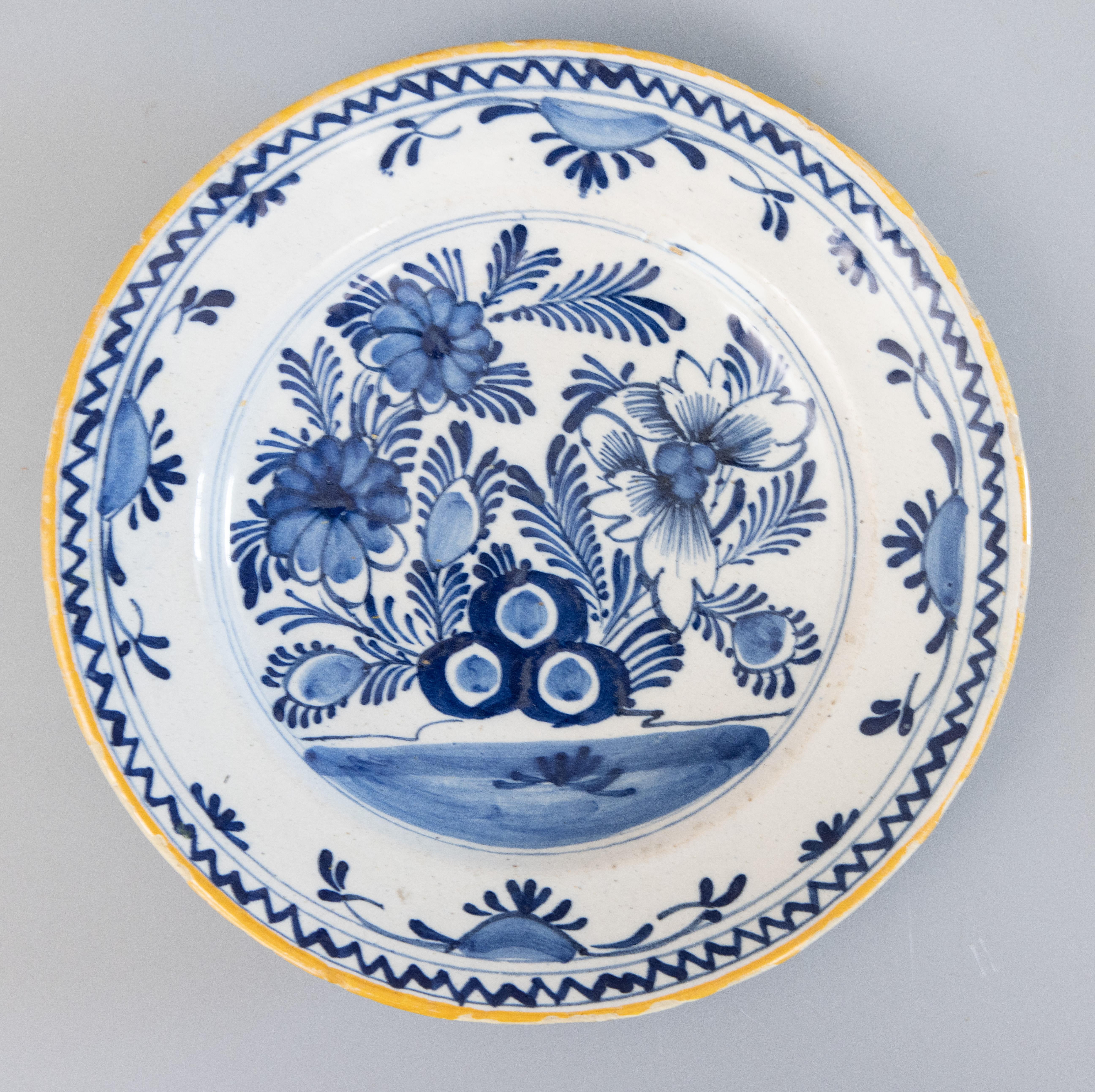 A gorgeous pair of antique 18th-Century Dutch Delft faience flower garden plates. These lovely plates have a hand painted floral and foliate design in cobalt blue and white with yellow gold rims. They would look fabulous displayed on a wall or in a