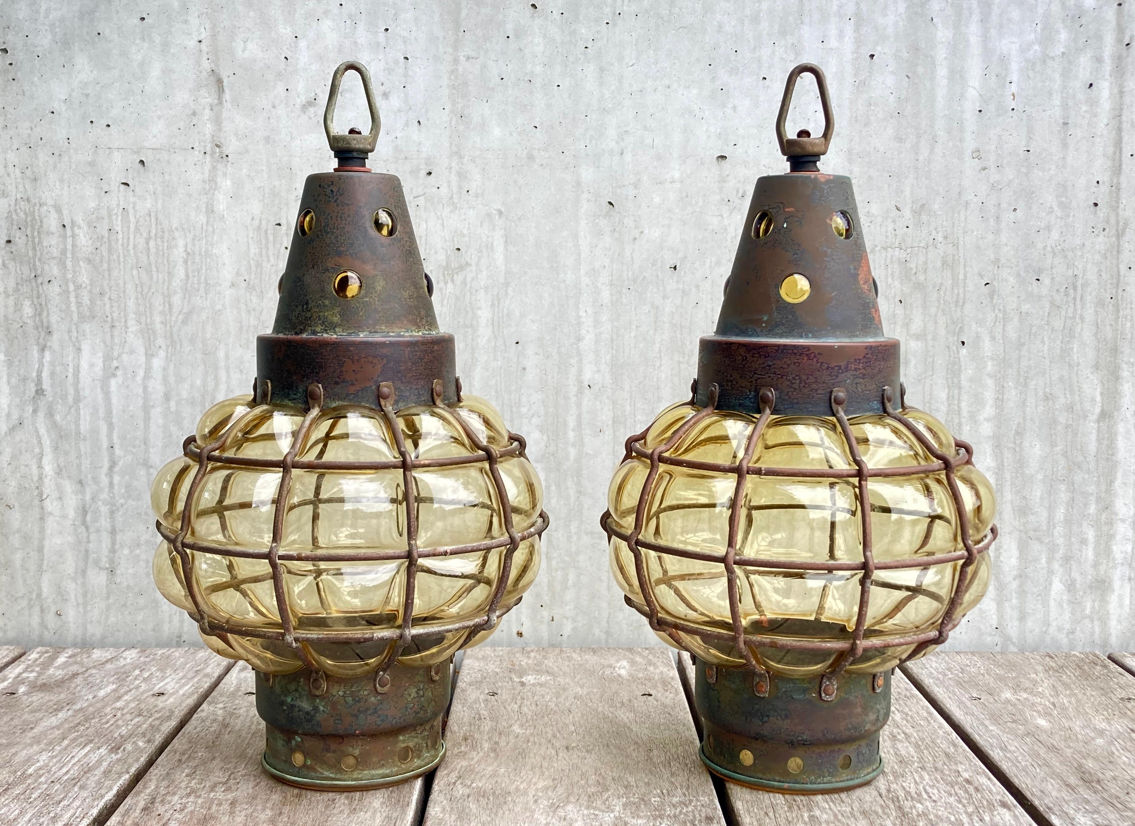 A rare set of two matching antique lanterns (pendant lamps). The lanterns have no maker's markings but most likely dates from the early 1900s. Their design is strongly inspired by the Arts and Crafts mouvement (1880-1920). The lanterns have been