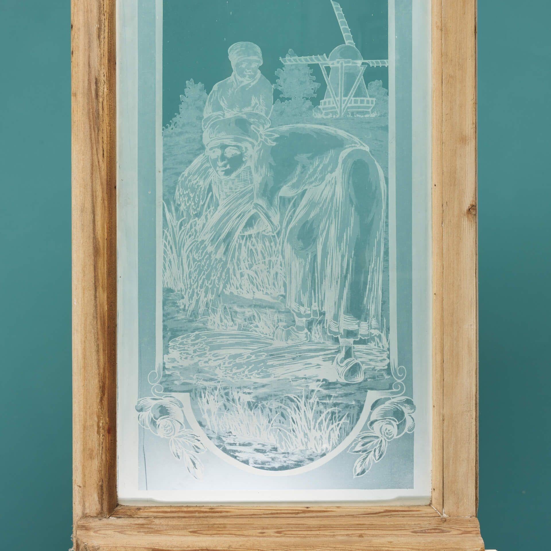 A pair of antique acid etched glass windows depicting a traditional rural scene of farmers in a wheat field. Originating from the Netherlands, this window portrays a classical Dutch scene, showing a man using a scythe or sickle to cut the wheat