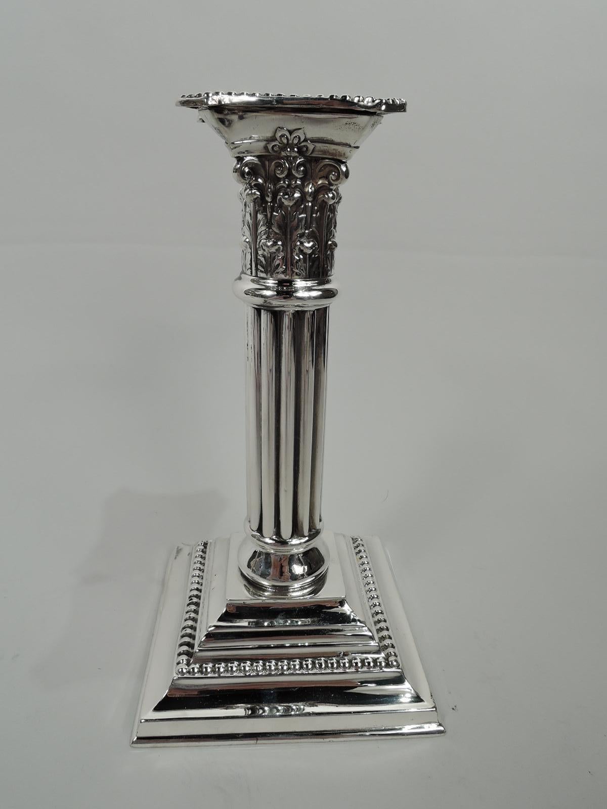 Pair of Edwardian Classical sterling silver candlesticks. Made by Mauser in New York, ca 1910. Each: Fluted shaft on stepped square base. Corinthian Composite capital. Concave and chamfered detachable bobeche. Beading. Fully marked including maker’s