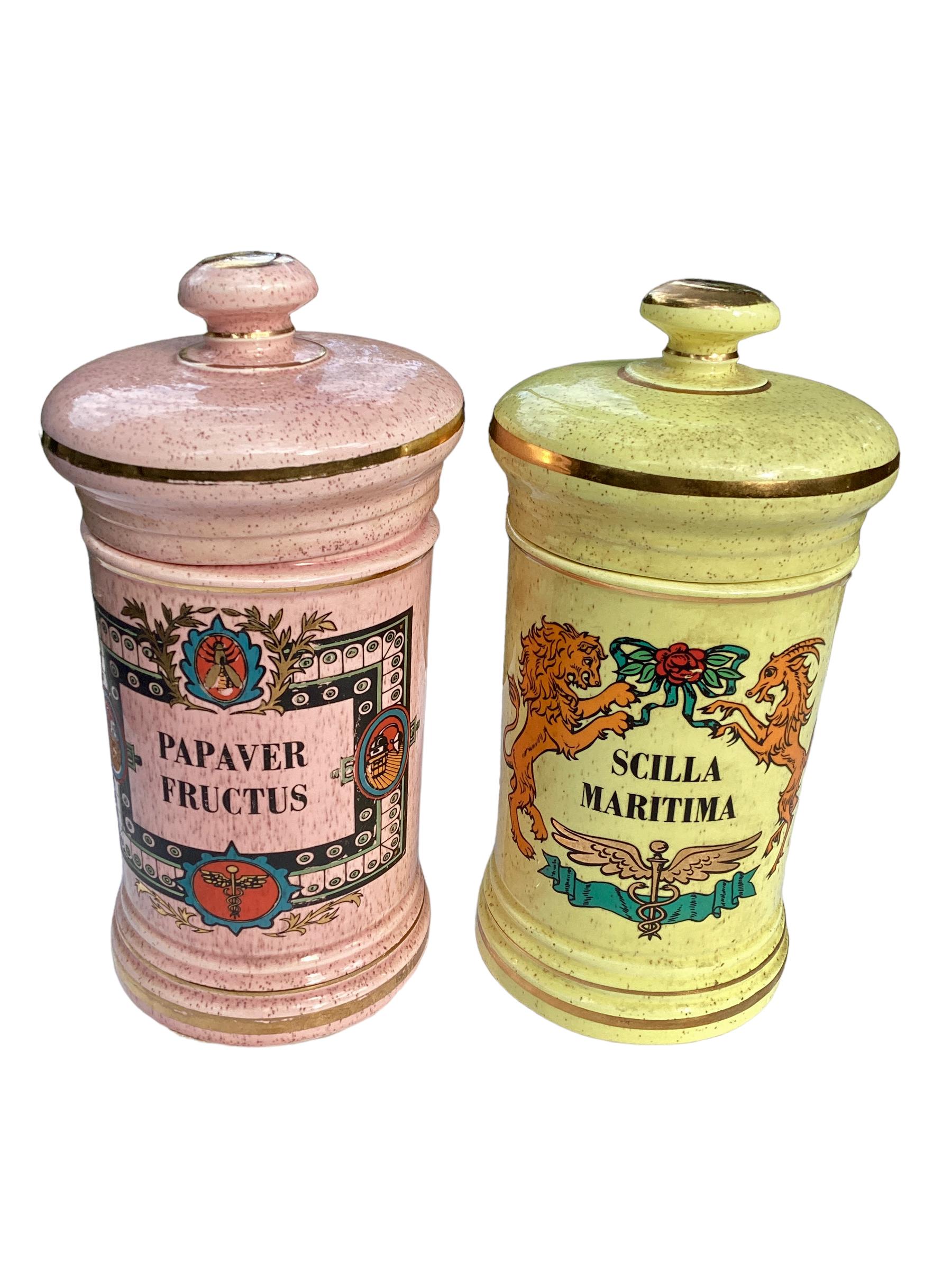 Pair of Antique American Covered Apothecary Jars. Vibrant colors in pink and yellow. The yellow jar is decorated with a lion and a ram and the pink one has various decorative objects including an insect and the symbol of a pharmacy. Both are trimmed