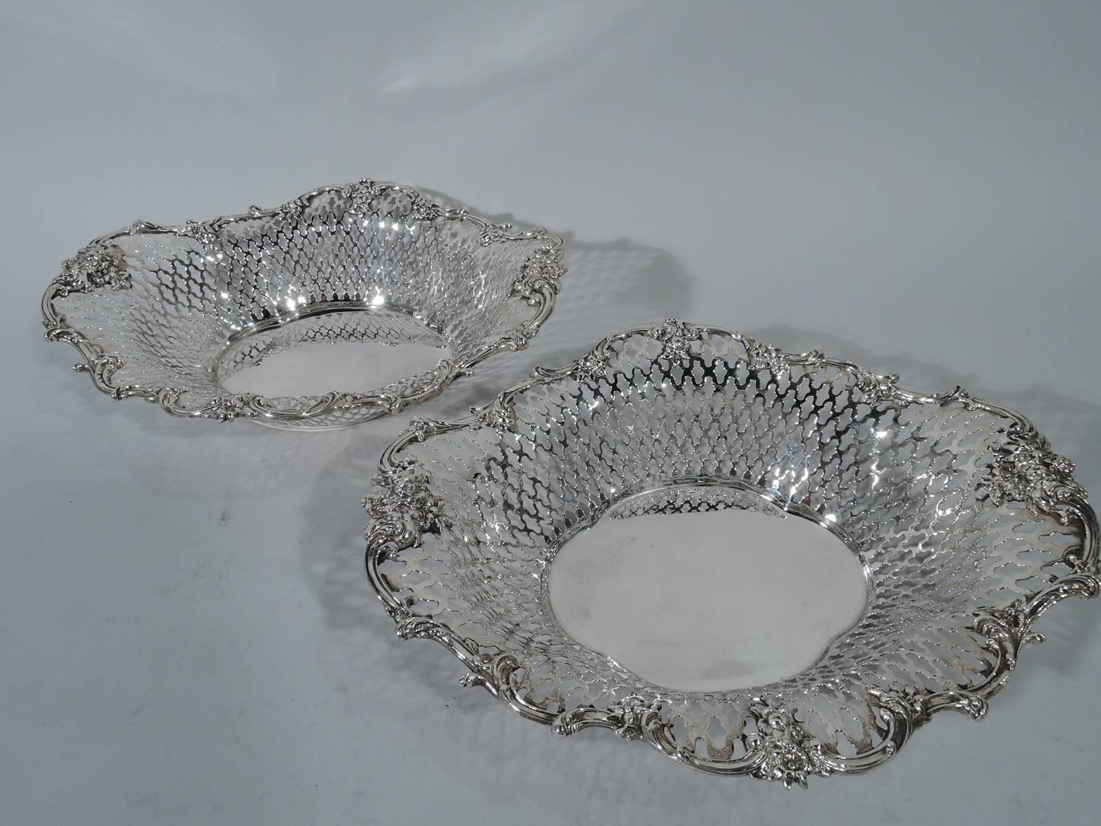 Pair of Edwardian sterling silver baskets. Made by Roger Williams (later part of Gorham) in Providence. Each: Solid quatrefoil well with tapering sides and wavy rim. Sides have pierced quatrefoil pattern. Rim has applied scrolls and flowers.