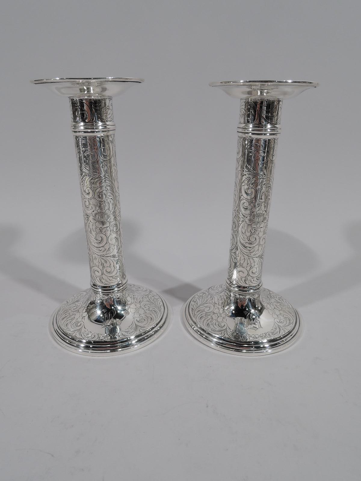 Pair of turn-of-the-century sterling silver candlesticks. Made by Black, Starr & Frost in New York. Each: Columnar shaft with ribbed bands at top and bottom on stepped and gently raised foot. Plain integral bobeche. Shaft and foot engraved with