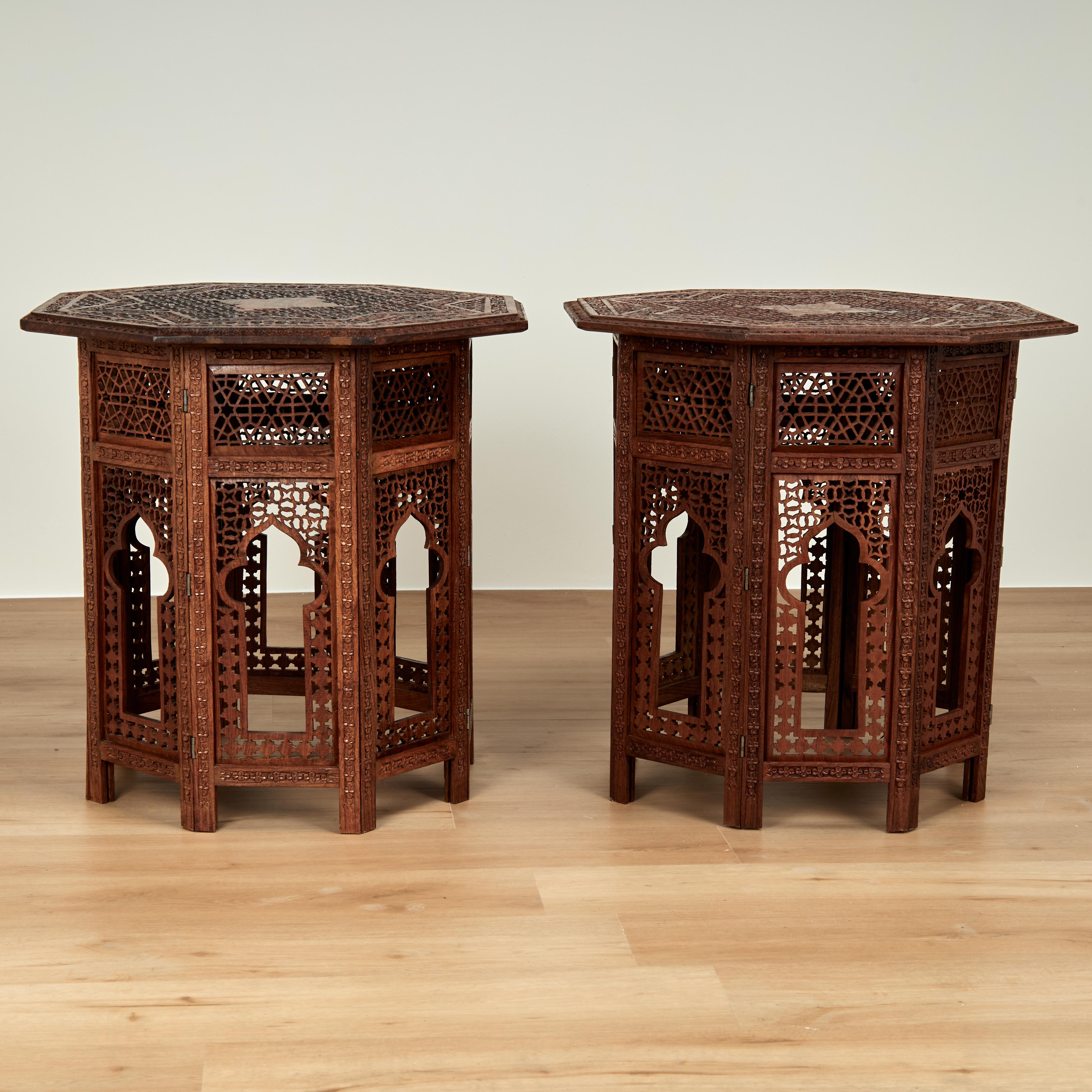 Outstanding pair of antique Anglo Indian stands crafted in indigenous mahogany having octagon tops ambitiously hand carved with geometric and floral motifs on eight sided carved bases with open fretwork and architectural arches.