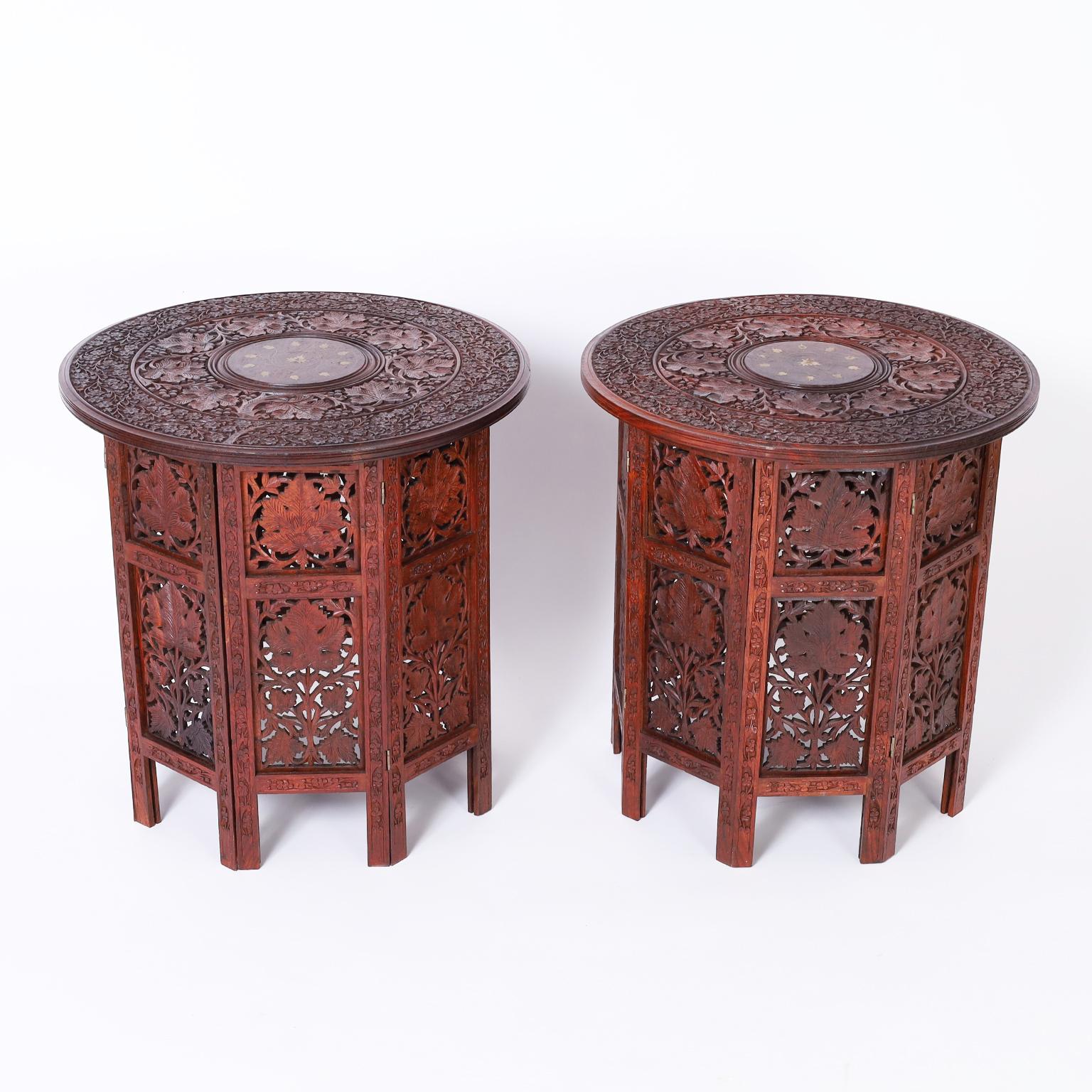 Pair of Anglo Indian stands crafted in mahogany with round tops having a center medallion with floral brass inlays surrounded by leaf carvings. The octagon bases have floral carvings with open fretwork.