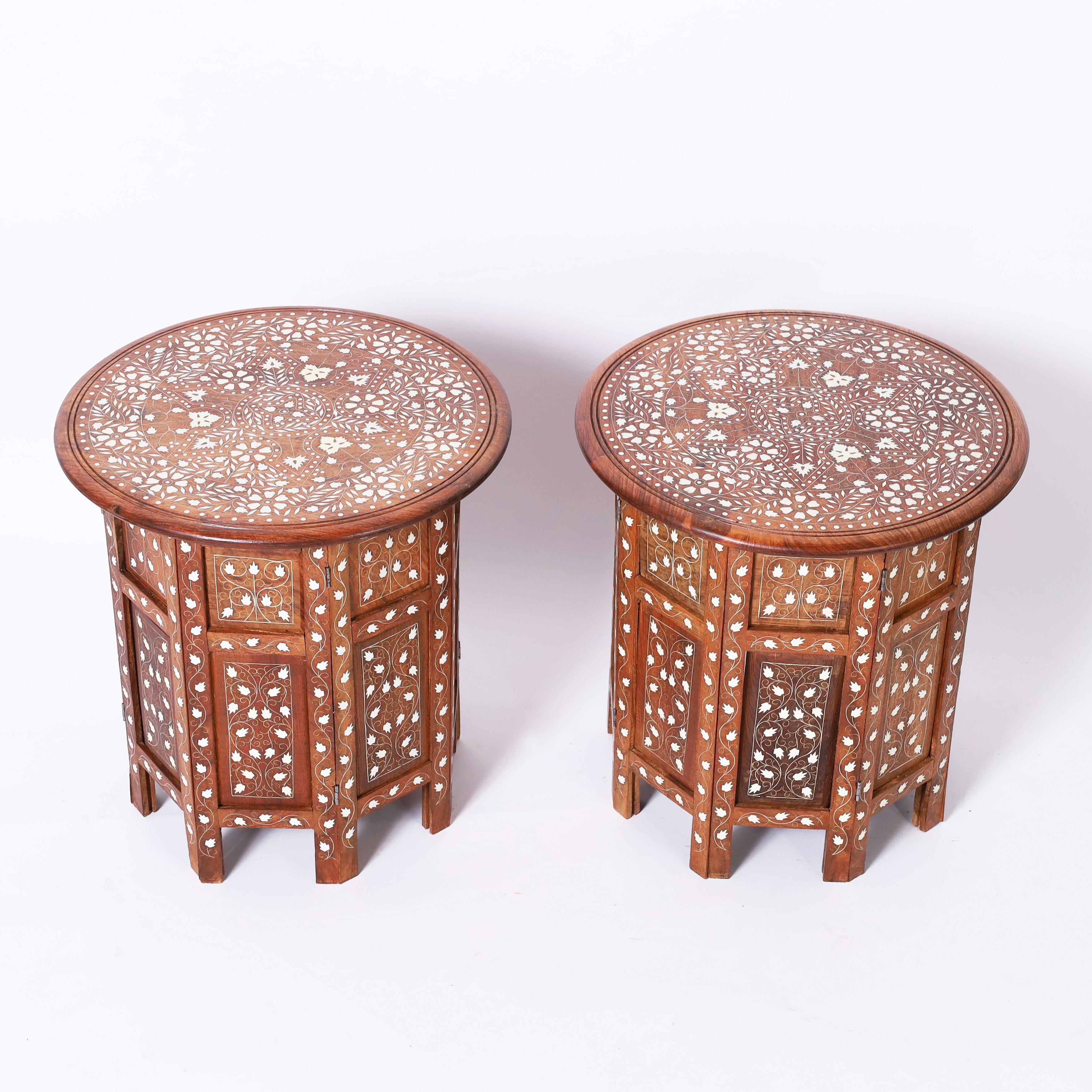 Standout pair of Anglo Indian Stands or tables crafted in teak wood having round tops with elaborate floral bone inlays on octagon paneled bases with matching floral bone inlays. 