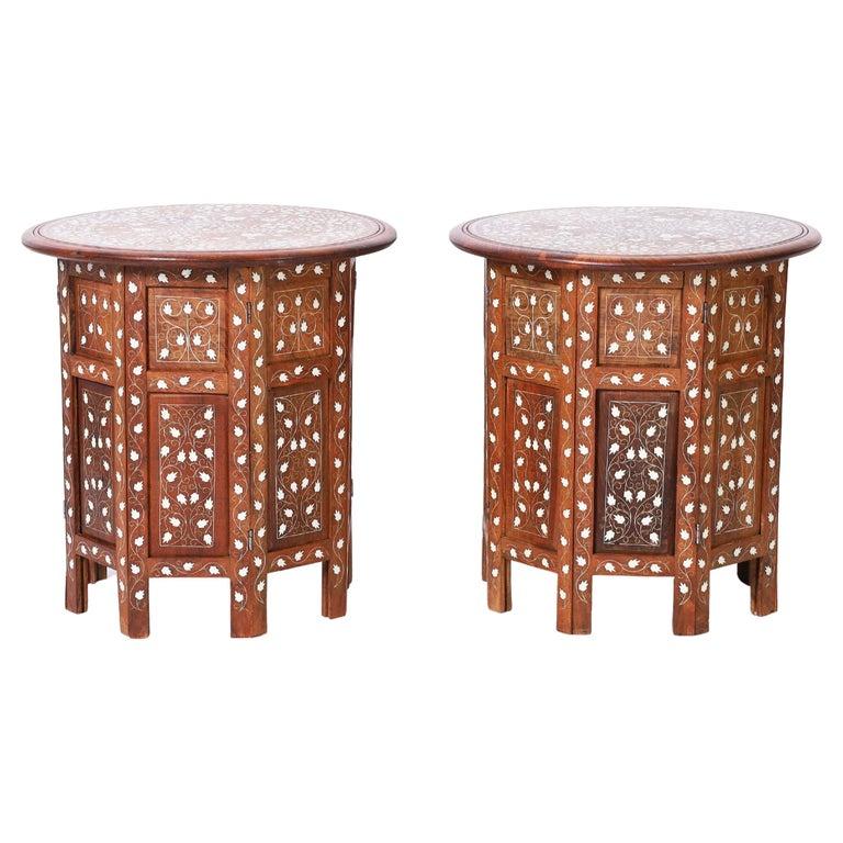 Standout pair of Anglo Indian Stands or tables crafted in teak wood having round tops with elaborate floral bone inlays on octagon paneled bases with matching floral bone inlays. 