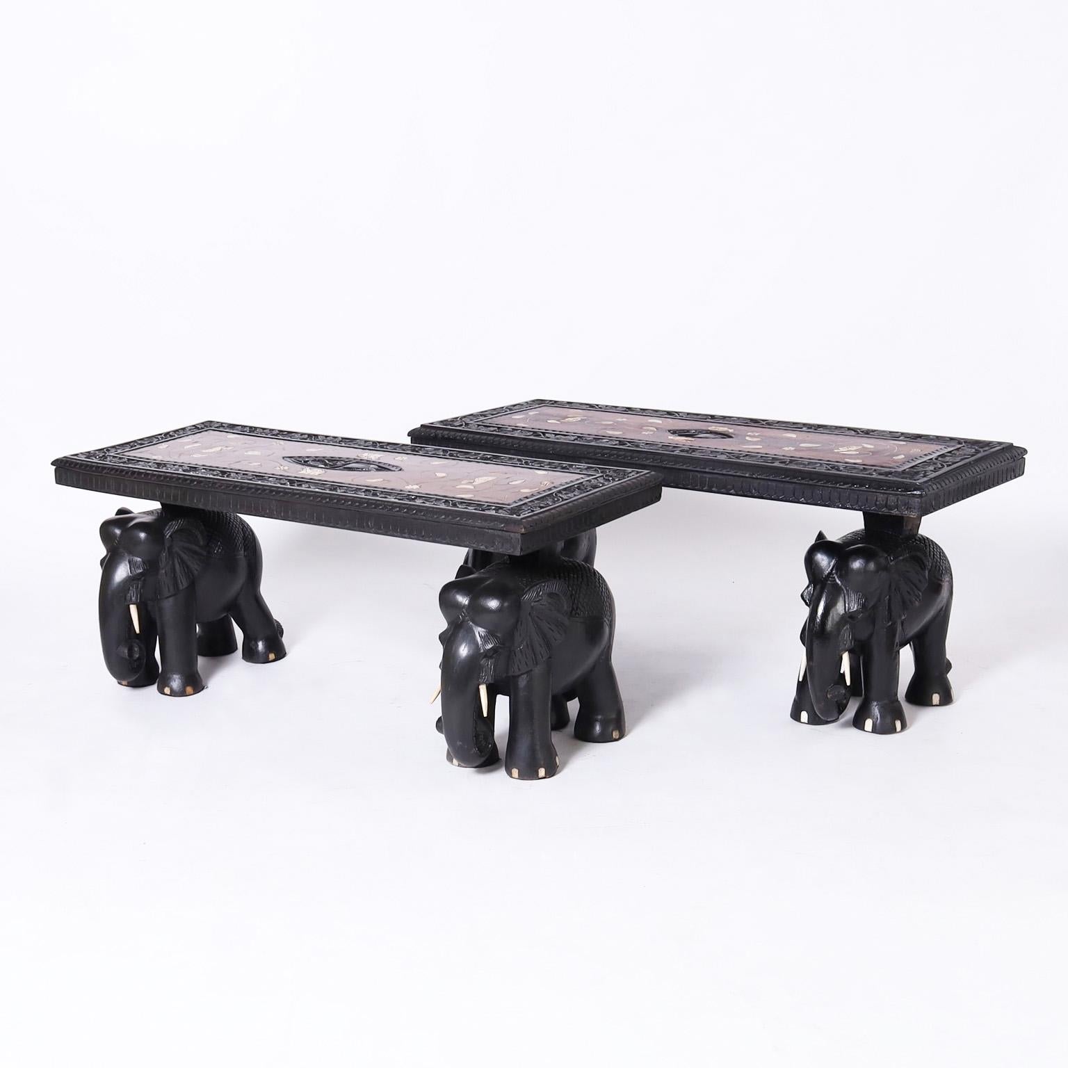 Rare and remarkable pair of Anglo Indian tables or benches crafted in mahogany and having tops with center elephant carvings surrounded by a field of inlaid bone in an ebonized carved floral border. The carved elephant bases are ebonized with bone