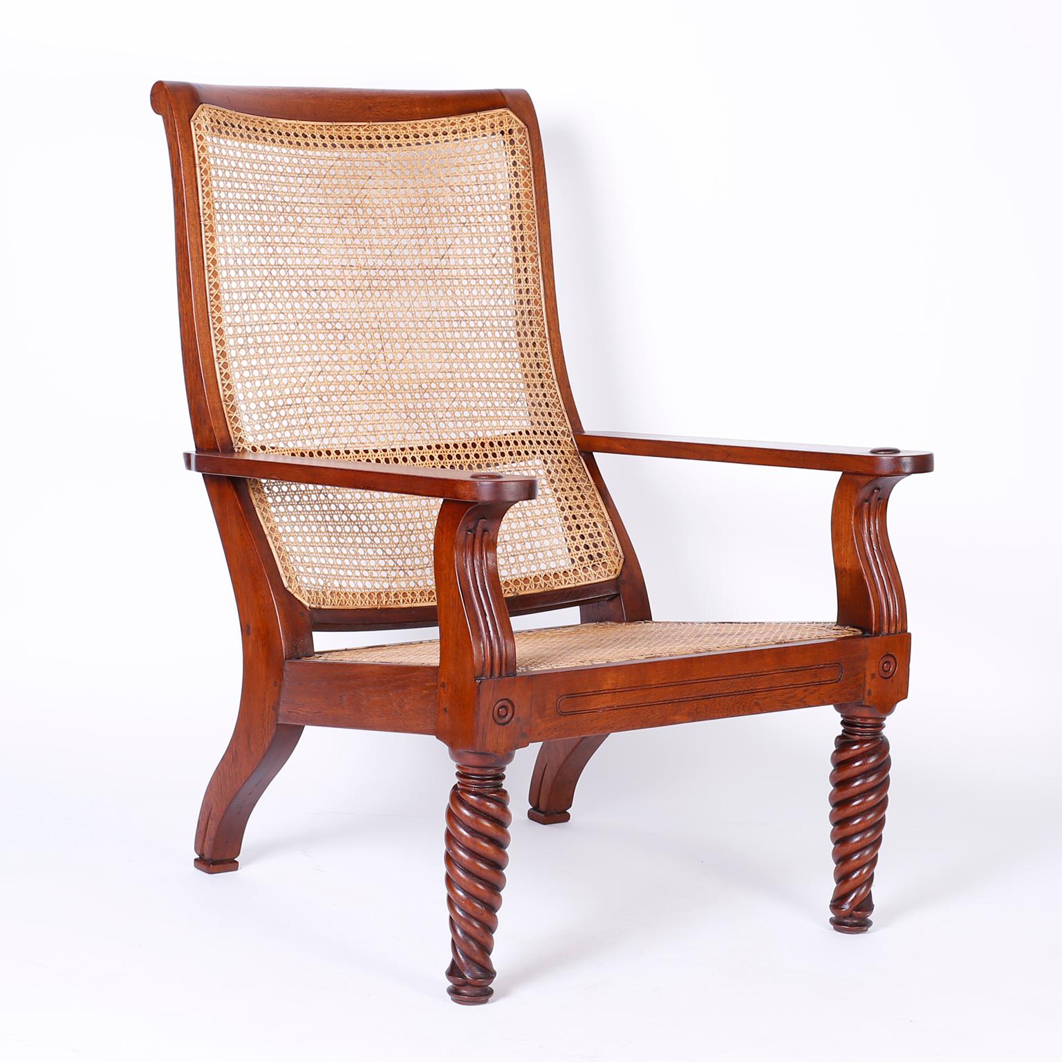 Refined pair of Anglo-Indian British Colonial plantation chairs handcrafted with mahogany featuring hand caned backs and seats, pegged construction, turned and twisted front legs and an overall elegant sophisticated form.