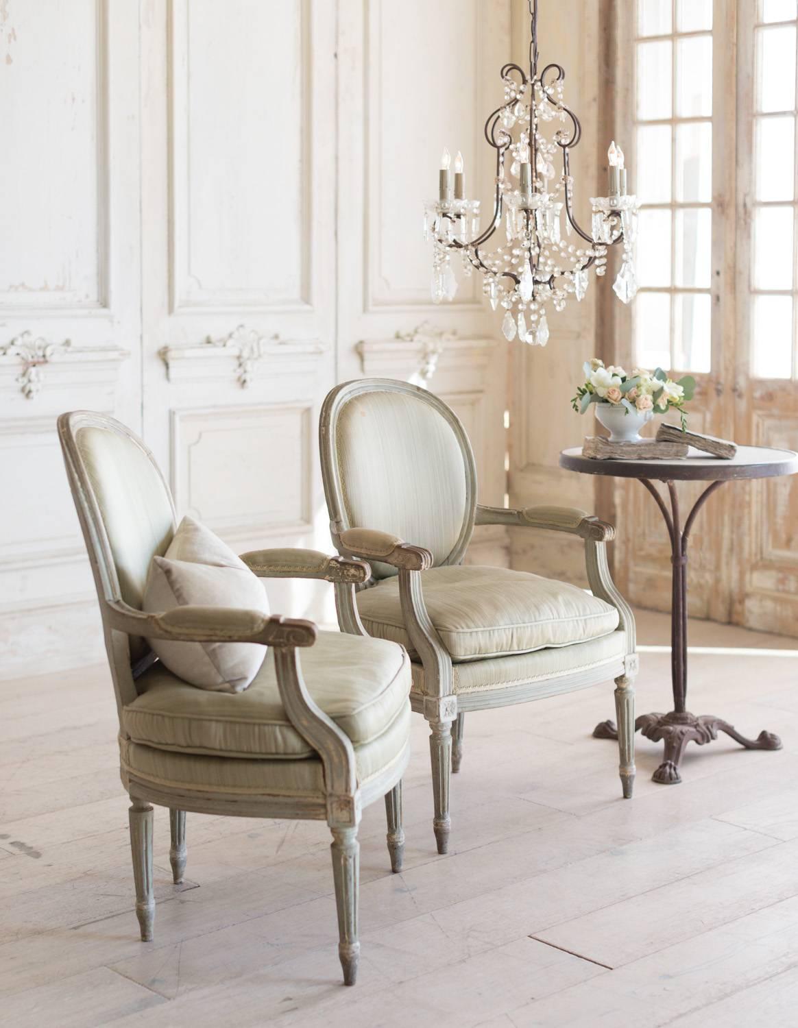 Sweet pair of antique armchairs in distressed Seafoam finish. The original, silky green fabric compliments the Louis XVI design. Simple column legs and small rosettes sit upon the legs. A beautiful addition to a dining or sitting area.