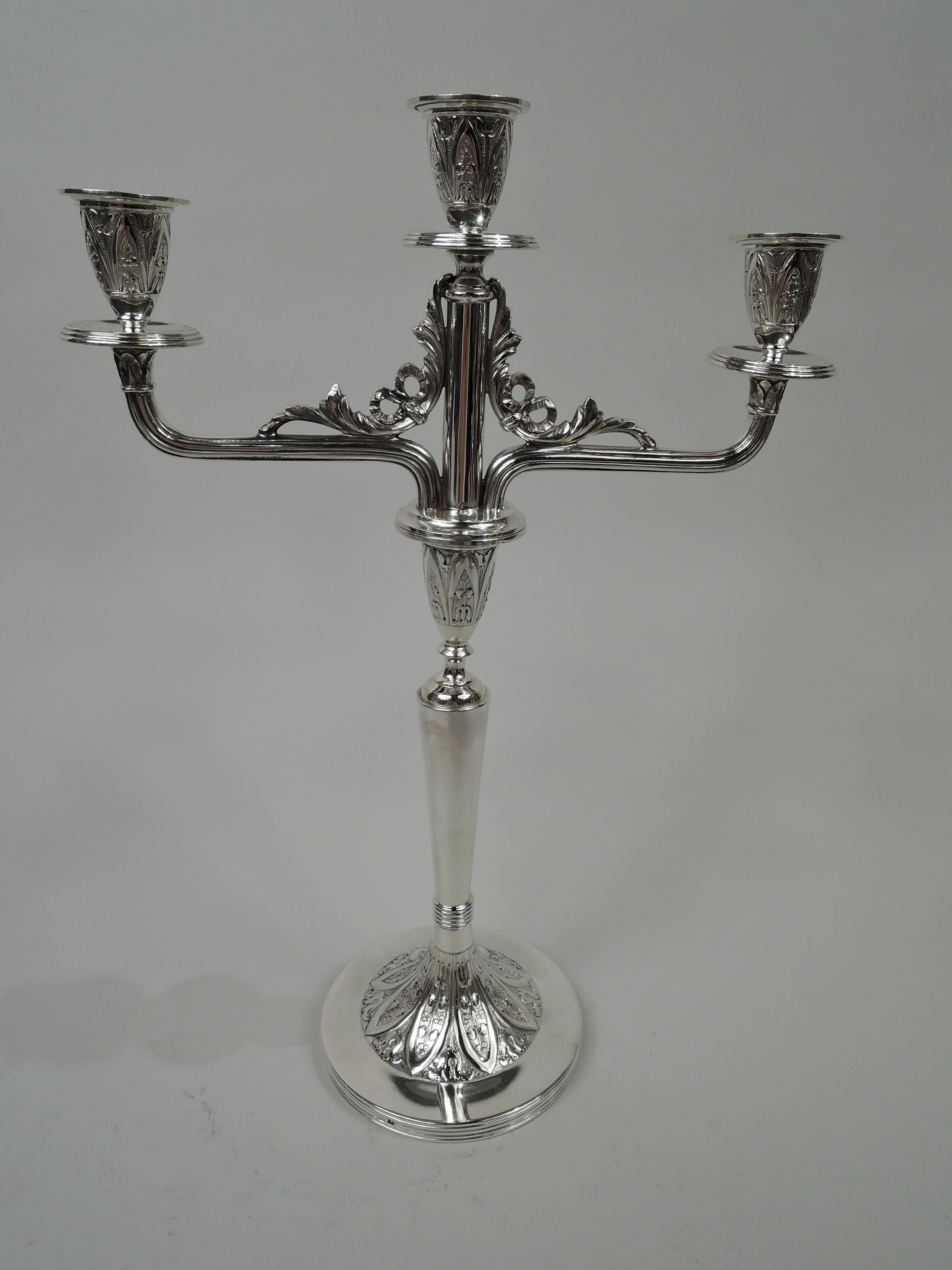 Pair of Austrian Aesthetic 800 silver 3-light candelabra, circa 1880. Each: Raised central light between bracket branches, each terminating in single socket. Sockets conical with stylized ornament comprising flowers set in leaf-and-dart borders on