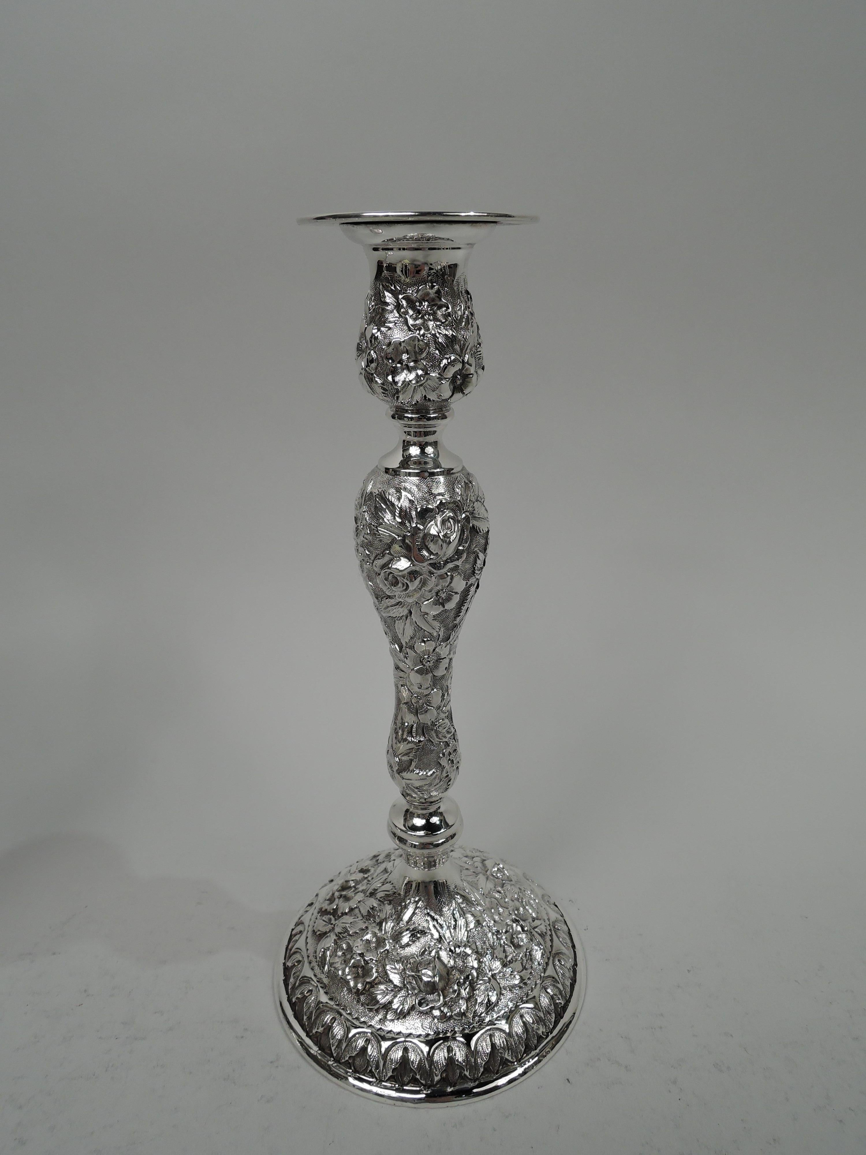 Pair of American Edwardian sterling silver candlesticks, ca 1910. Urn socket on baluster shaft on domed foot. Plain bobeche and knop. Allover floral repousse and leaf-and-dart foot border. Traditional form with historic regional ornament. Marks