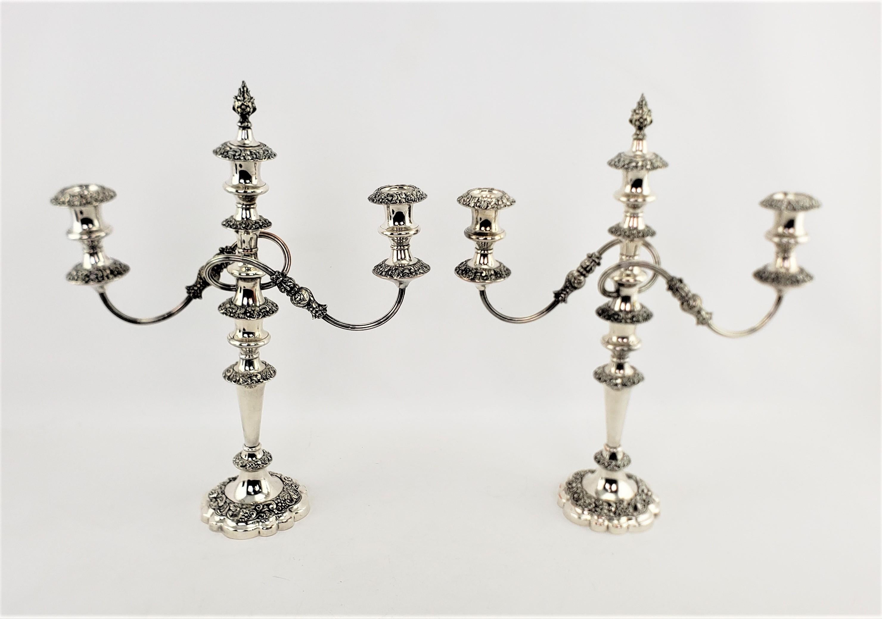 Este par de antiguos candelabros convertibles bañados en plata fueron fabricados por la renombrada empresa Barker-Ellis Silver de Inglaterra y datan aproximadamente de 1920, con un estilo victoriano. Los candelabros tienen tres copas que pueden