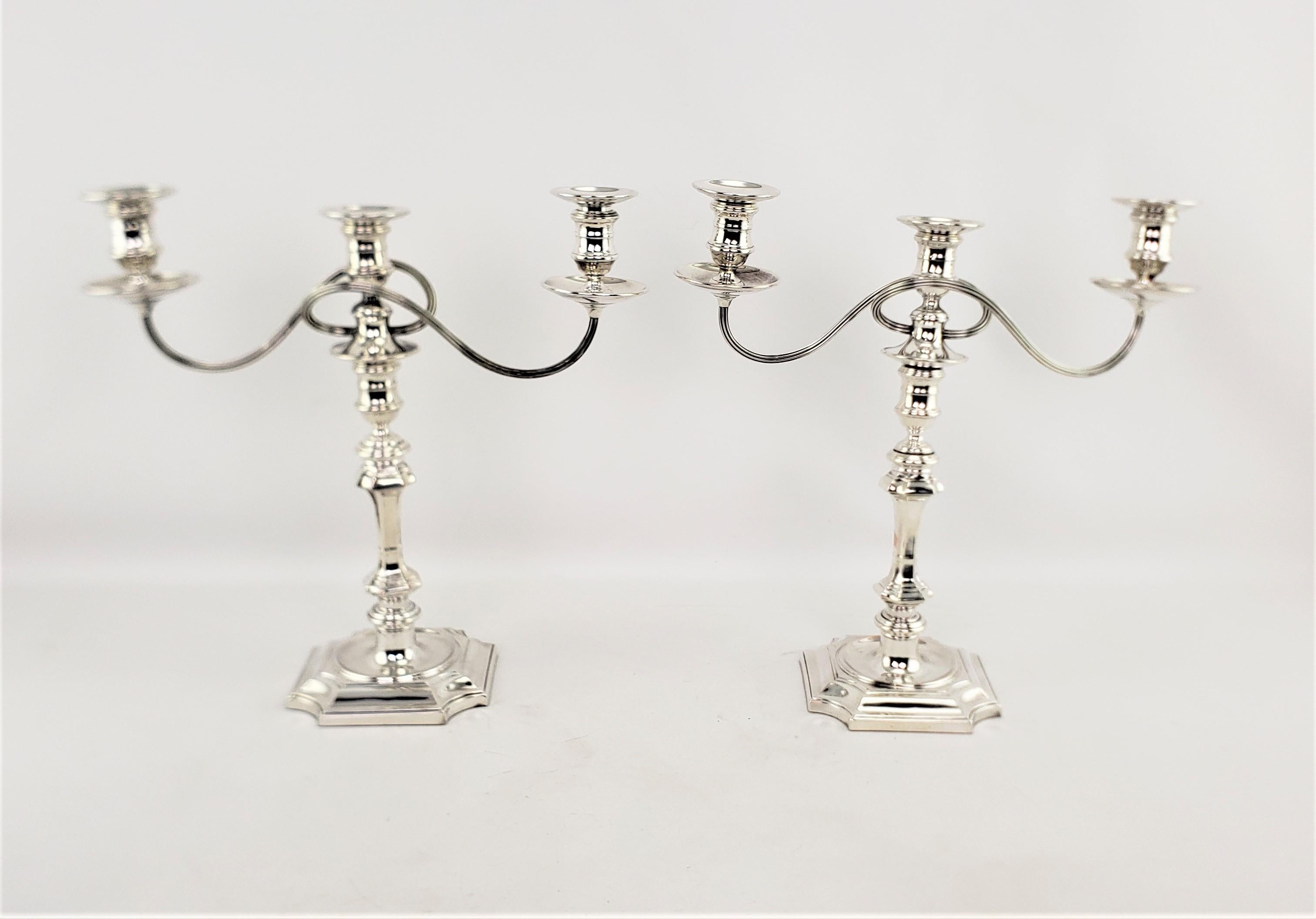 This pair of antique silver plated convertible candelabras were made by the renowned Barker-Ellis Silver company of England and date to approximately 1920 and done in a Victorian style. The candelabras have three candle holders on two curled arms,