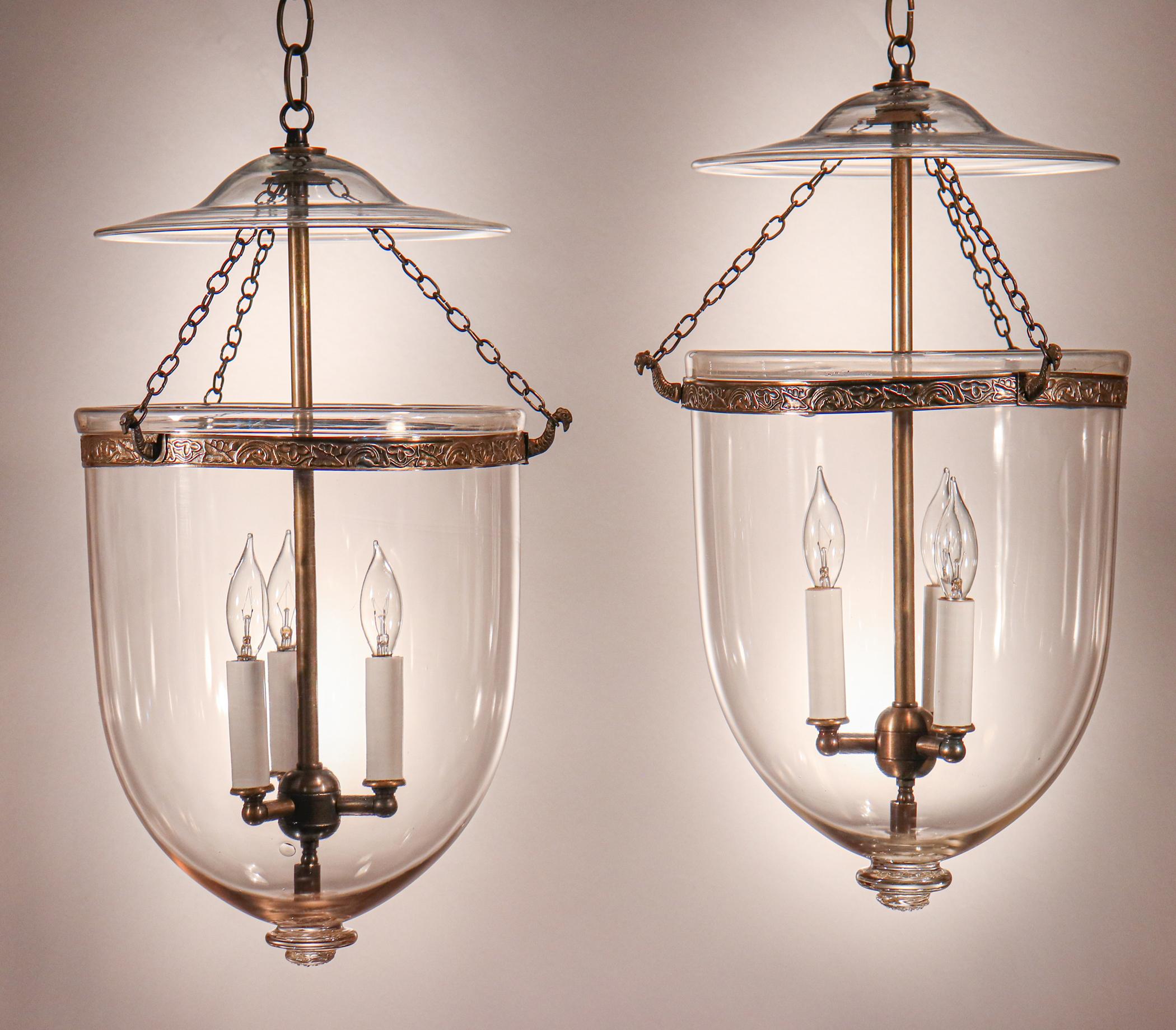 A pair of late-19th century English bell jar lanterns with excellent quality hand blown glass, beautiful form, and ample volume. These circa 1880 pendants feature classic smoke bells/lids and embossed brass fittings, which were replaced at some