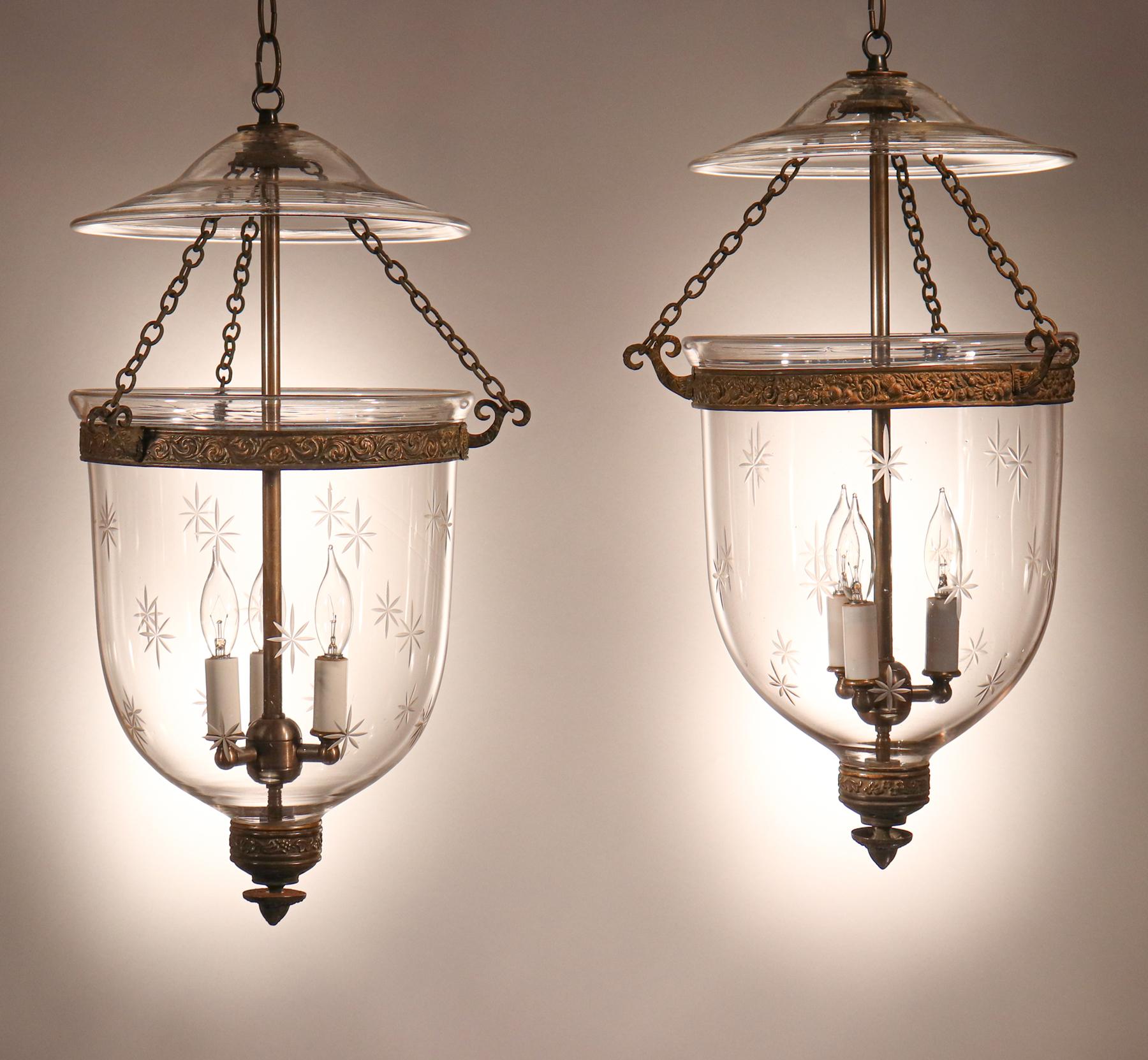 A lovely pair of antique, hand blown glass bell jar lanterns with an etched star motif from England. This well-matched pair of circa 1850 pendants features authentic period brass bands and matching finial/candleholder bases. An exceptional and rare
