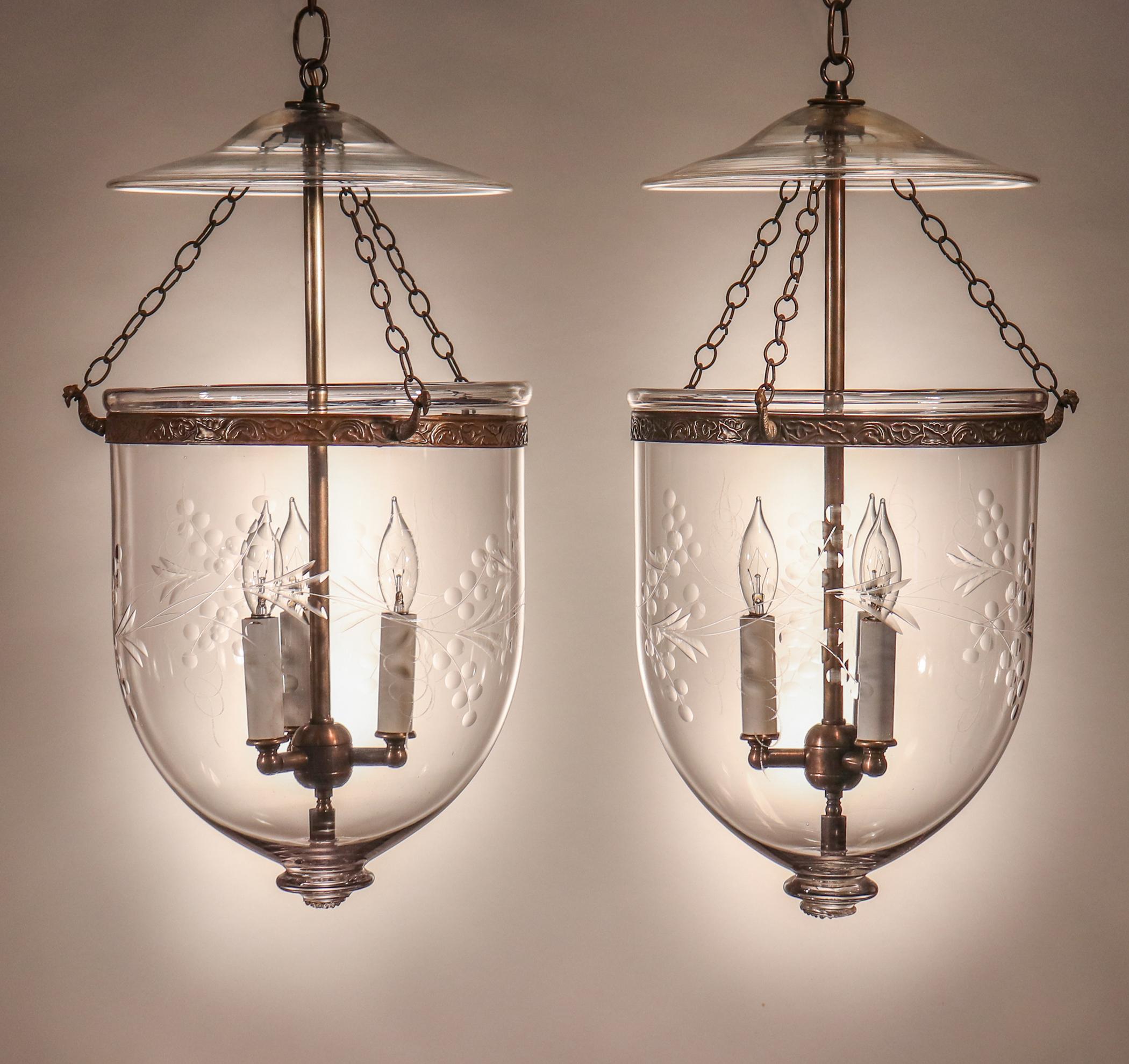 An exquisite pair of bell jar lanterns with excellent quality hand blown glass and an etched and polished vine motif. These circa 1880 English pendants feature their original glass smoke bells and chains. The brass bands, which have a meandering