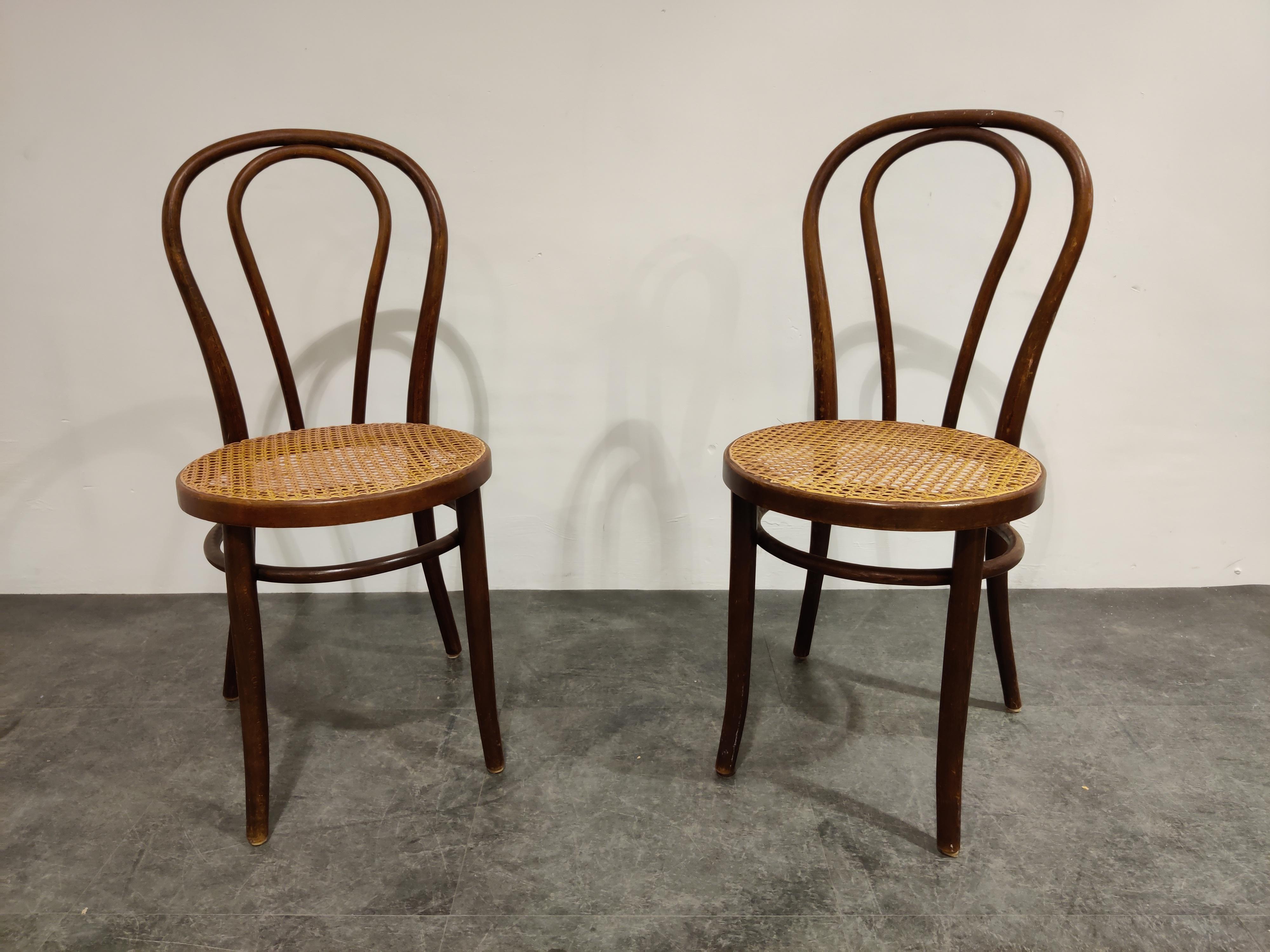 Pair of dark brown bentwooden dining chairs.

Stamped 'made in Romania'. 

We date them at early 1950s.

The cane seats are in good condition.

Dimensions:
Height 90cm/35