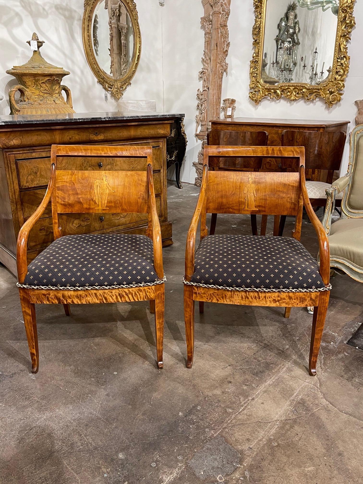 Exquisite pair of antique flame mahogany Biedermeier armchairs. There is an inlaid image of a person on each chair and they are upholstered in a pretty patterned fabric. So unique and exceptional quality!