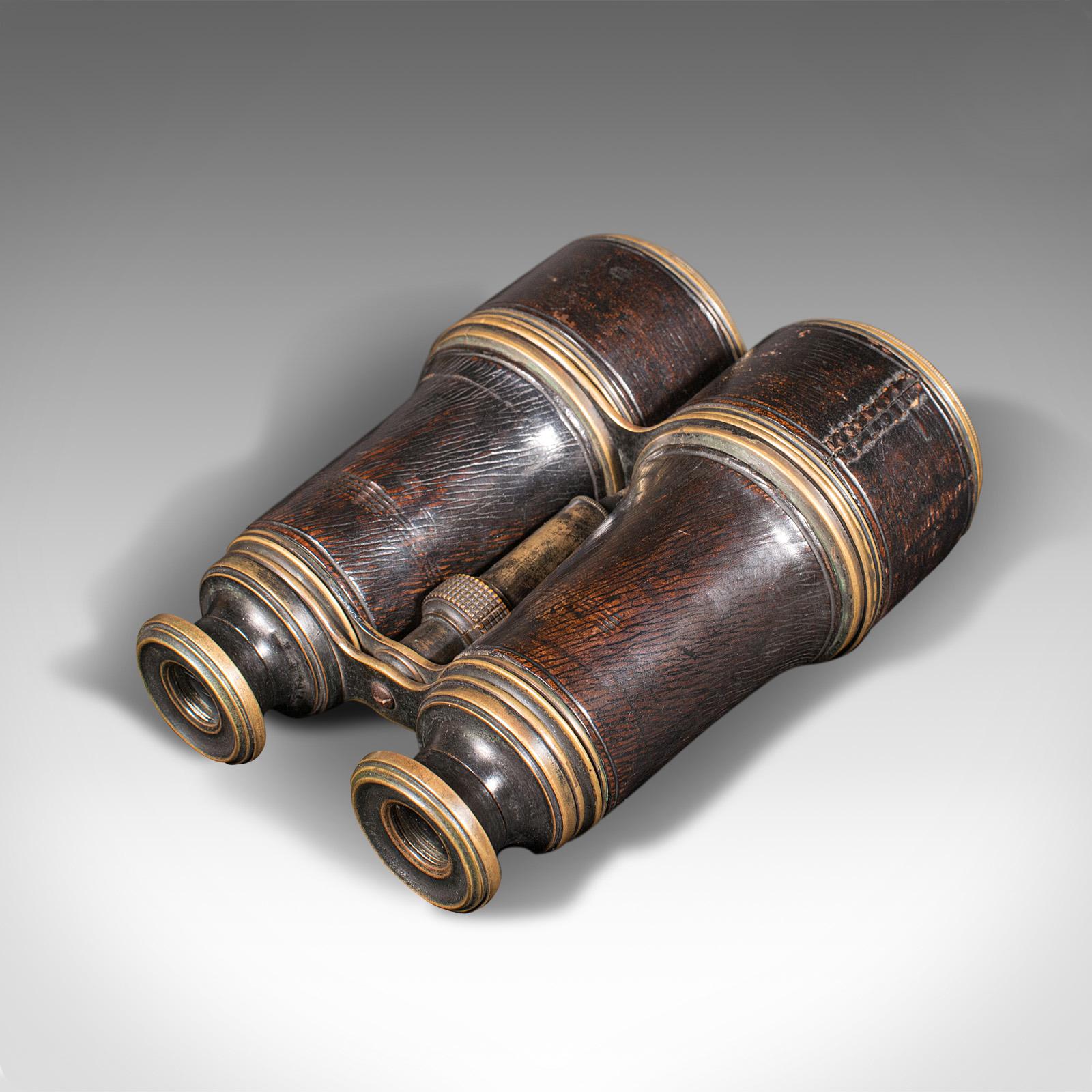 This is a pair of antique binoculars. An English, brass and leather optical instrument, dating to the early 20th century, circa 1920.

Wonderfully patinated pair of early 20th century binoculars
Displaying a desirable aged patina