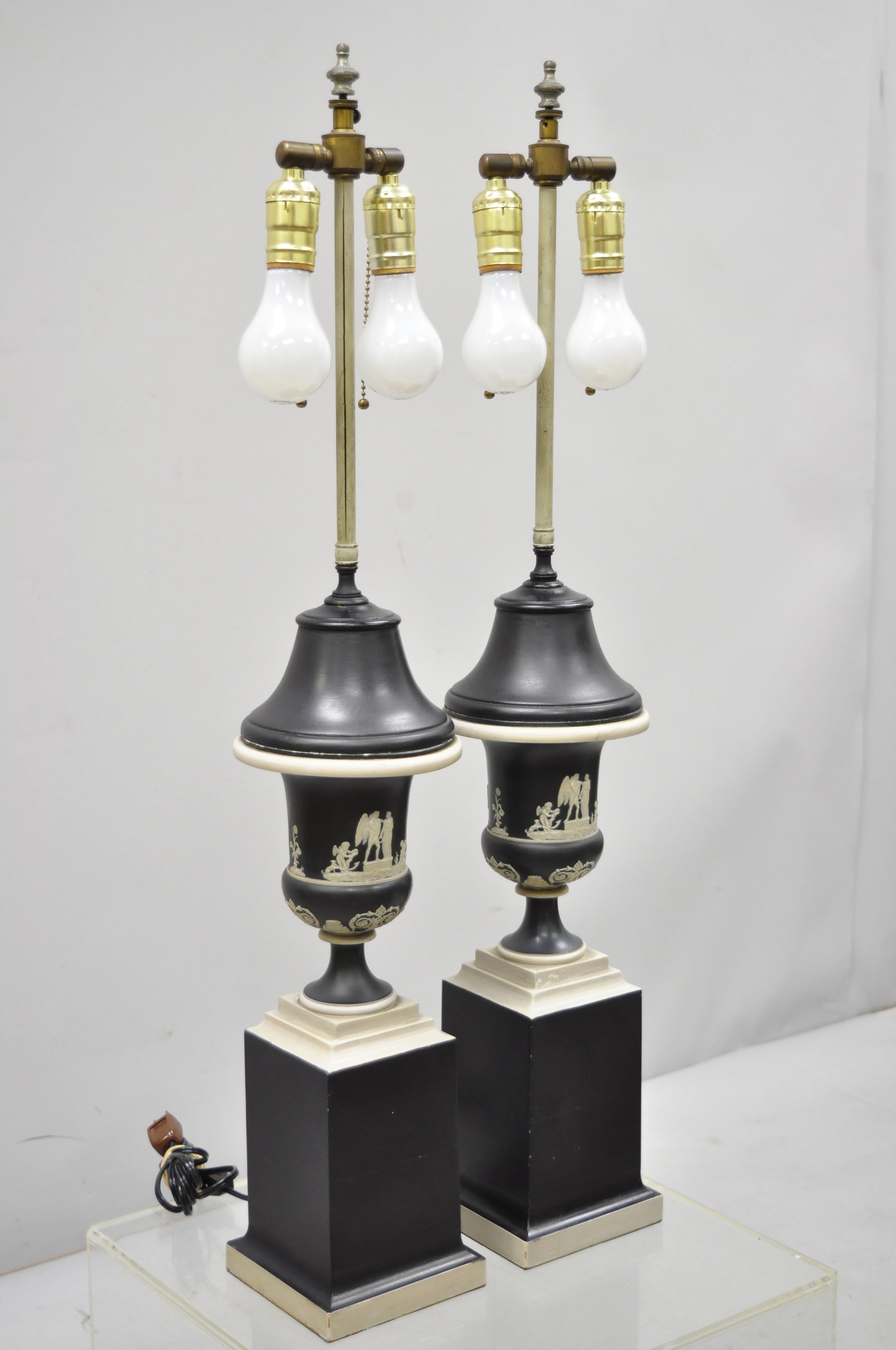 Pair of antique black and white Wedgwood jasperware urn table lamps. Listing includes porcelain urn form bodies, wooden base, dual sockets, white Greek figures, very nice antique item. Believed to be Wedgwood, circa early 20th century. Measurements: