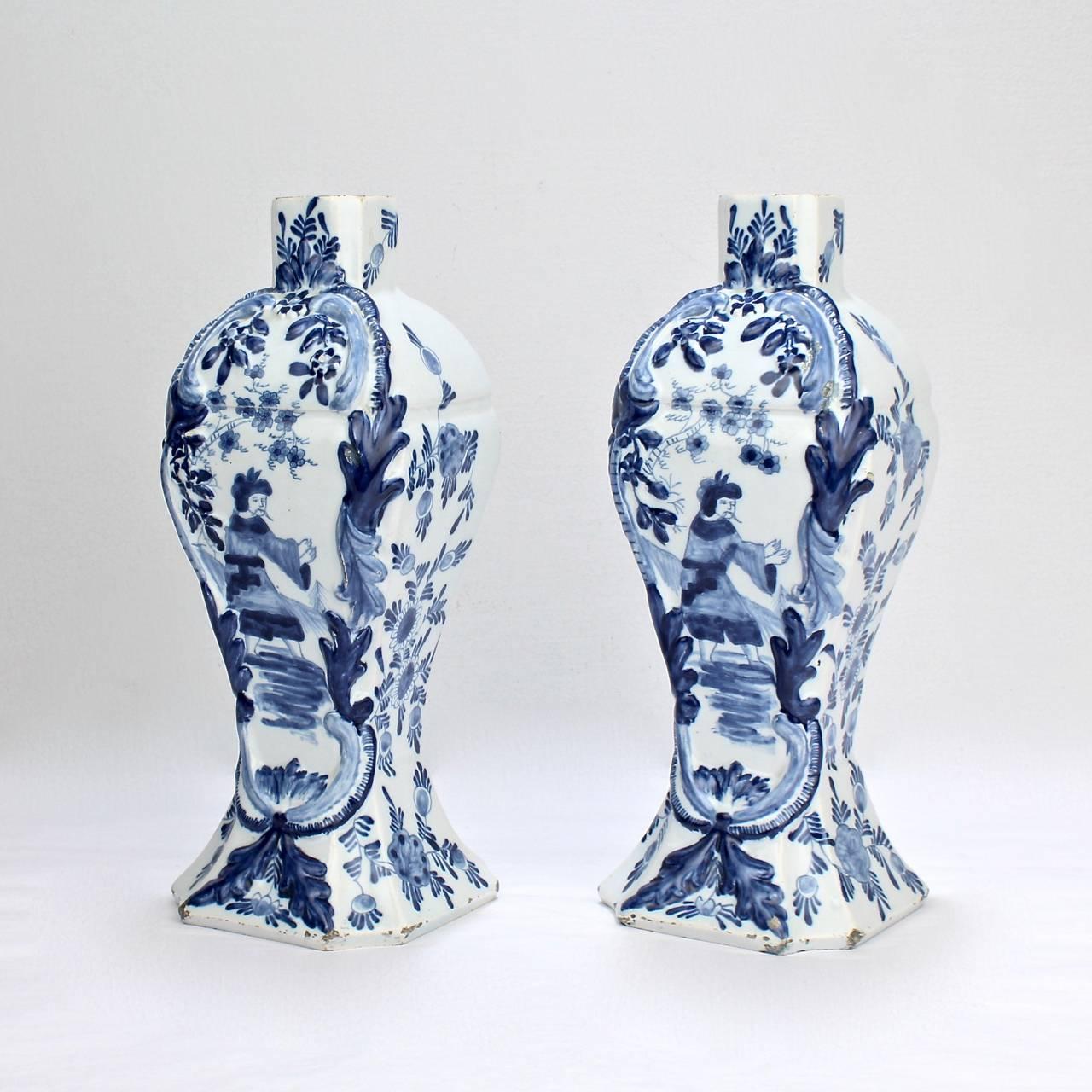 A fine pair of antique Dutch Delft garniture vases. 

Each is of an elegant, narrow form and depicts a Chinoiserie scene in the typical Dutch blue and white palette.

Dating to the 18th or 19th century.

Bases both marked with a blue