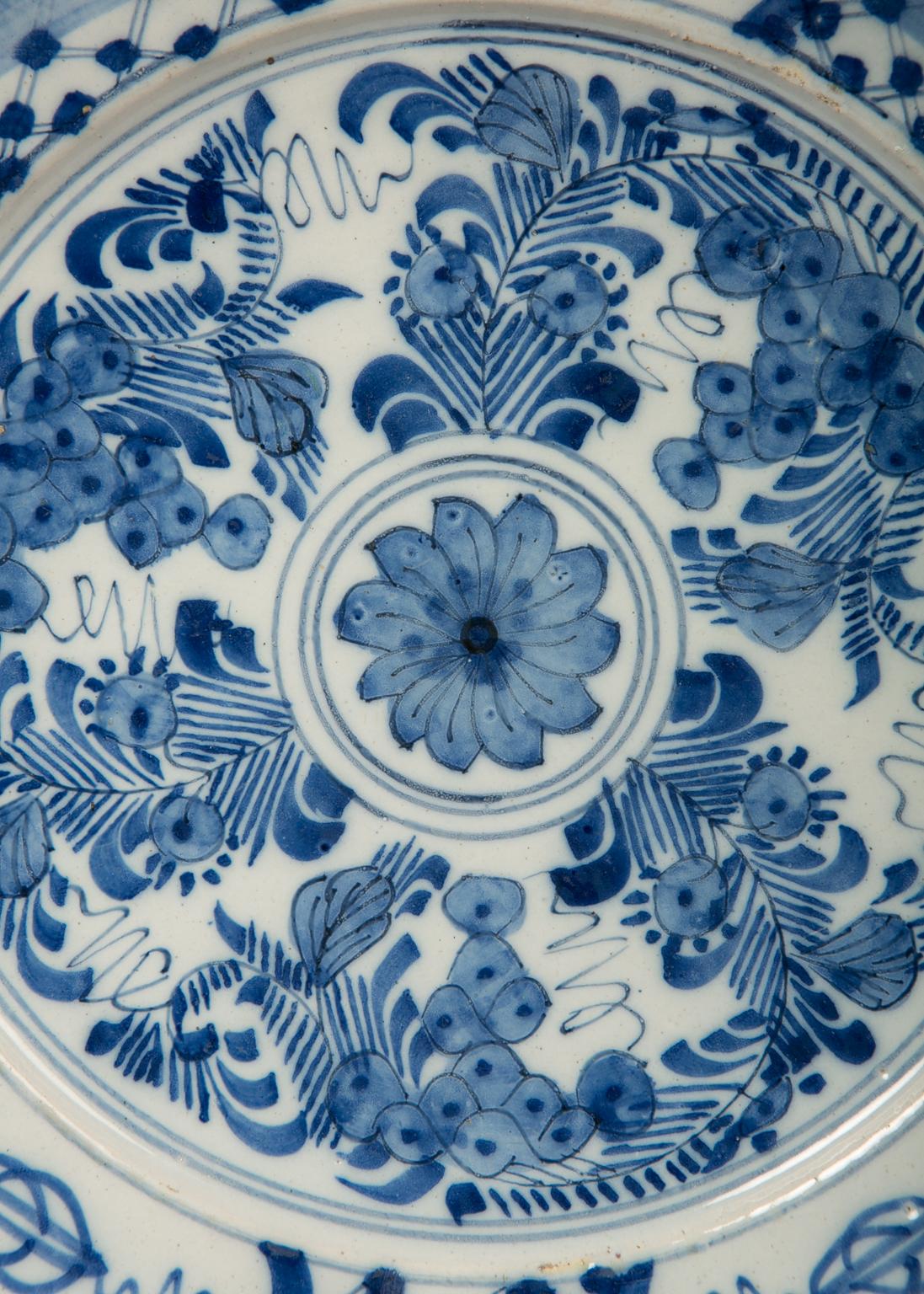 We are pleased to offer this pair of antique Dutch Delft blue and white pancake plates fully painted with a chrysanthemum encircled by flowering plants. The wide border is decorated with 