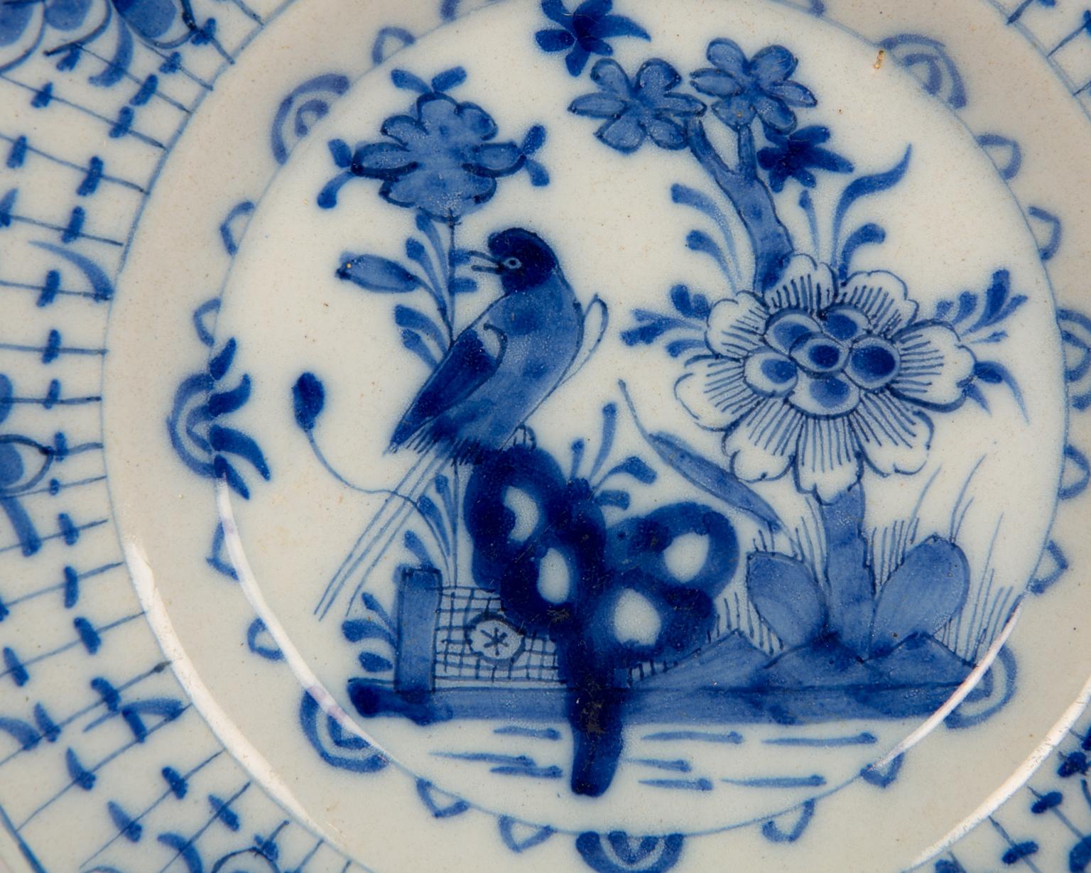 We are pleased to offer this pair of antique Blue and White Dutch Delft dishes painted in the center with a garden scene featuring a bird atop a dark blue scholar's rock. Around the bird we see flowers and behind it a garden fence.
 Made in the in