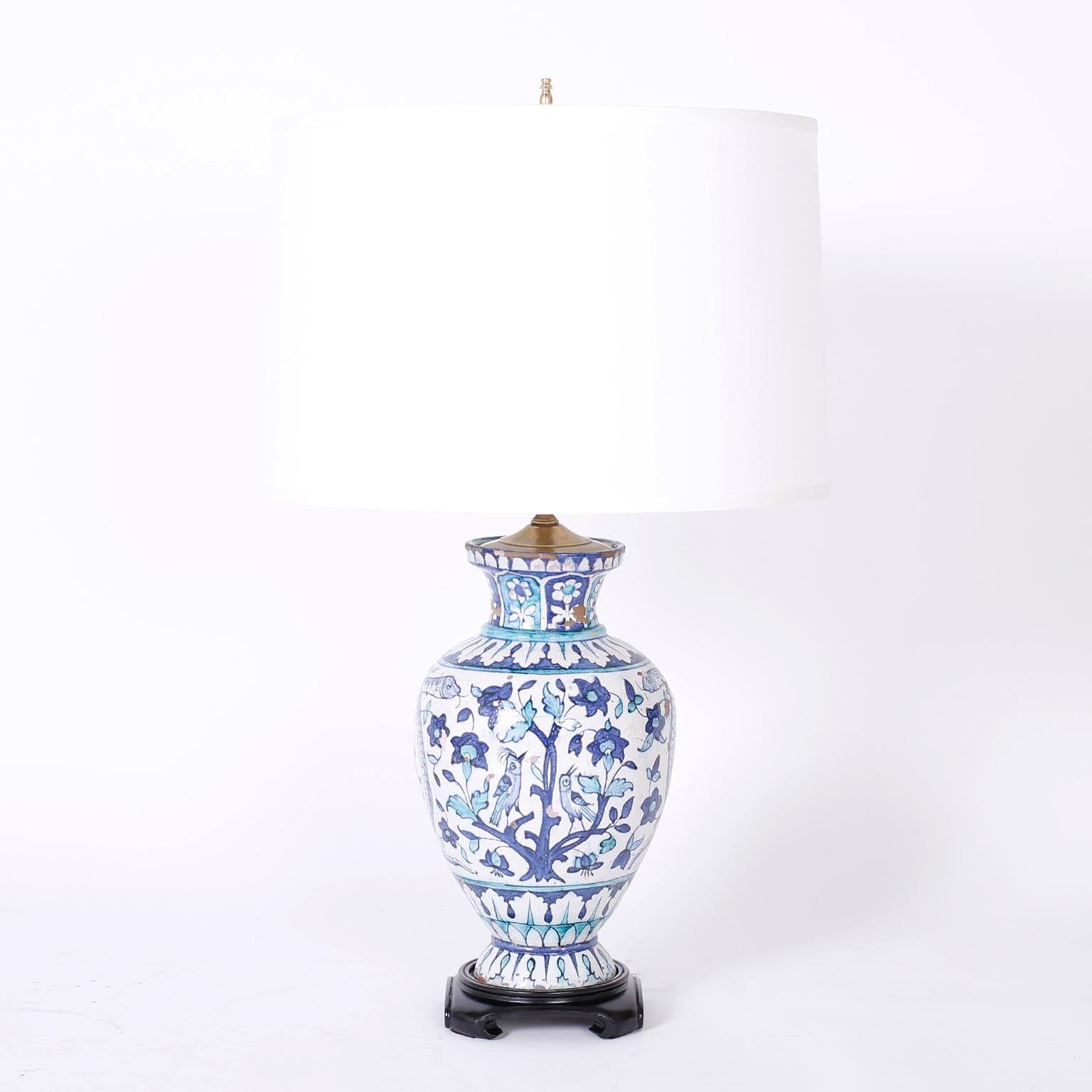 Charming pair of table lamps crafted in terra cotta featuring hand painted birds, trees, flowers, and snakes under glaze, once antique vases now fitted as lamps with the expected wear.