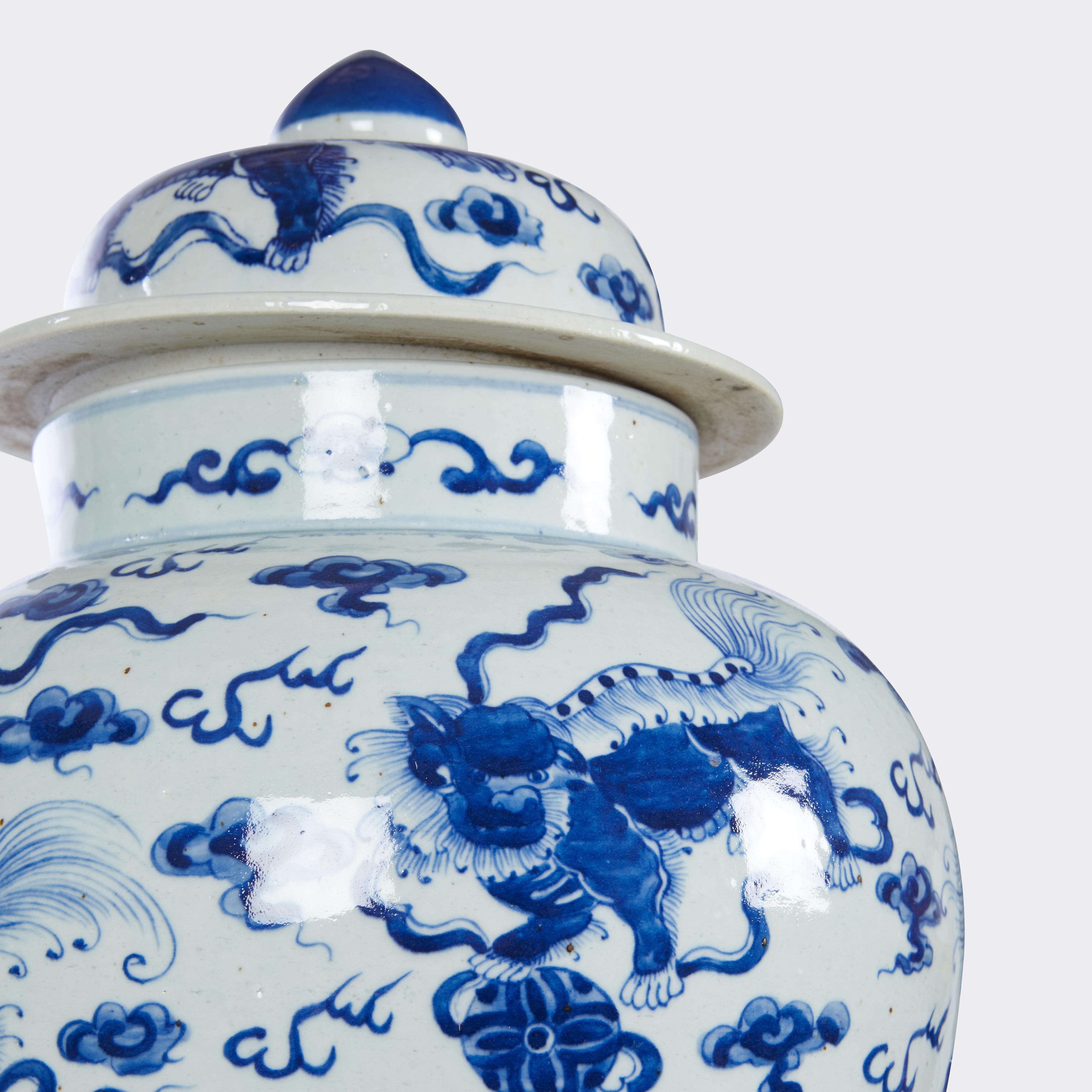 Pair of blue and white vases with covers, bodies and lids decorated with fu-dogs and stylized cloud motifs. Circa 1970s.