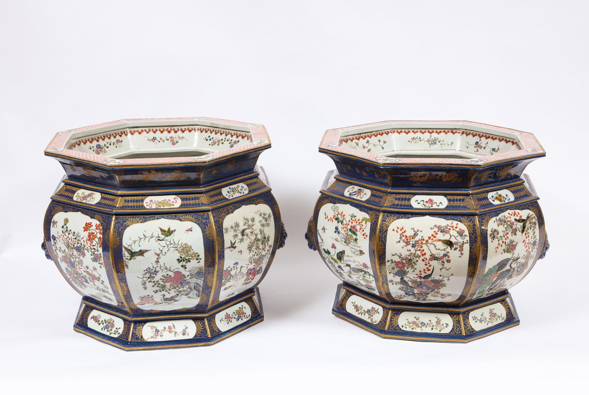 A fabulous and unusual pair of antique blue Chinese porcelain octagonal shaped fishbowls/ jardeniers painted with cartouches of flowers, birds, and fruit. Each of the bowls have beautifully designed foo-lion mask handles. The insides are elaborately