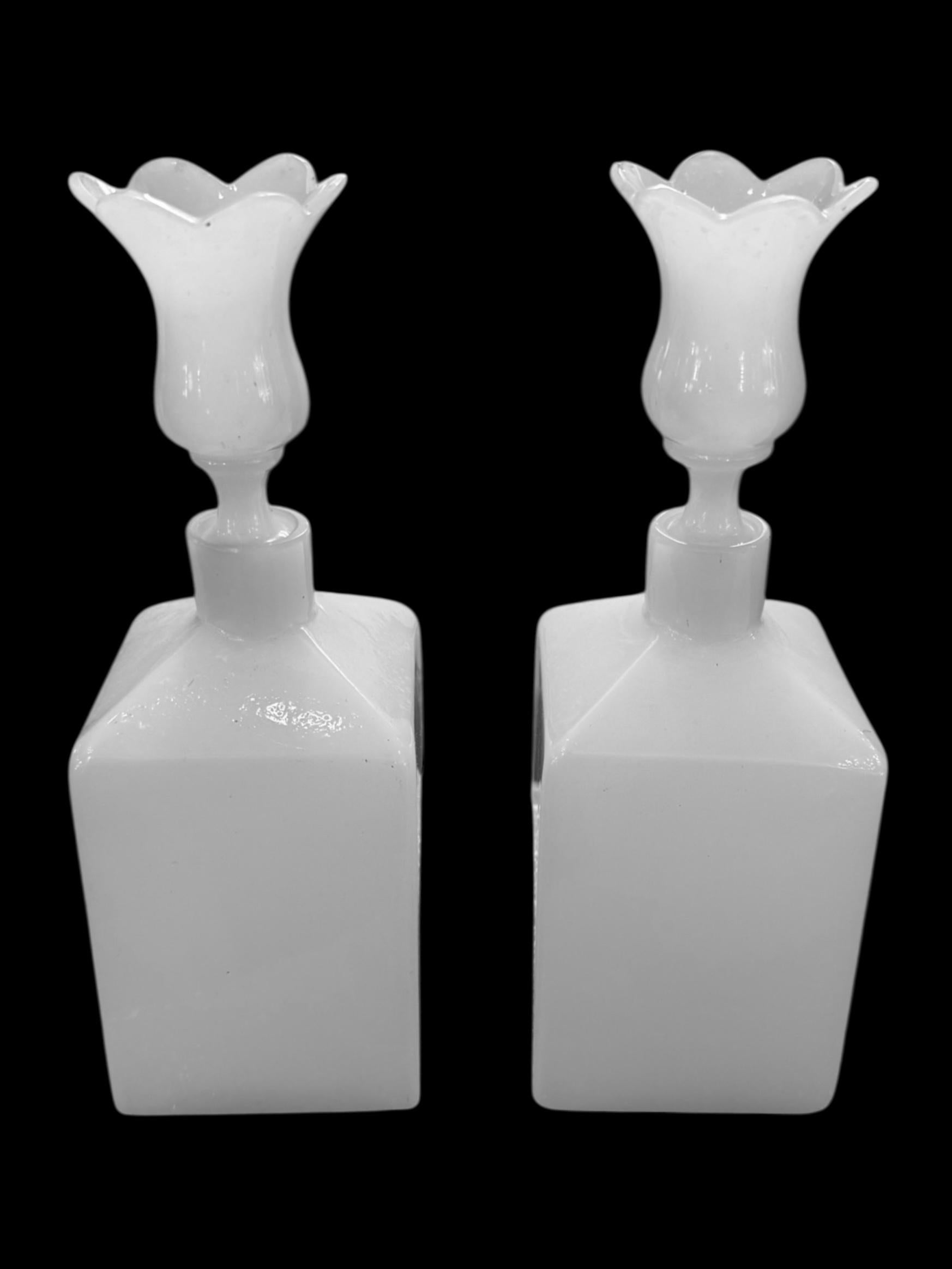 Add timeless elegance to your vanity or collection with this exquisite pair of antique Bohemian perfume bottles. Crafted from opaline milk glass, each bottle features a sleek square base topped with a beautifully flared floral stopper, evoking the