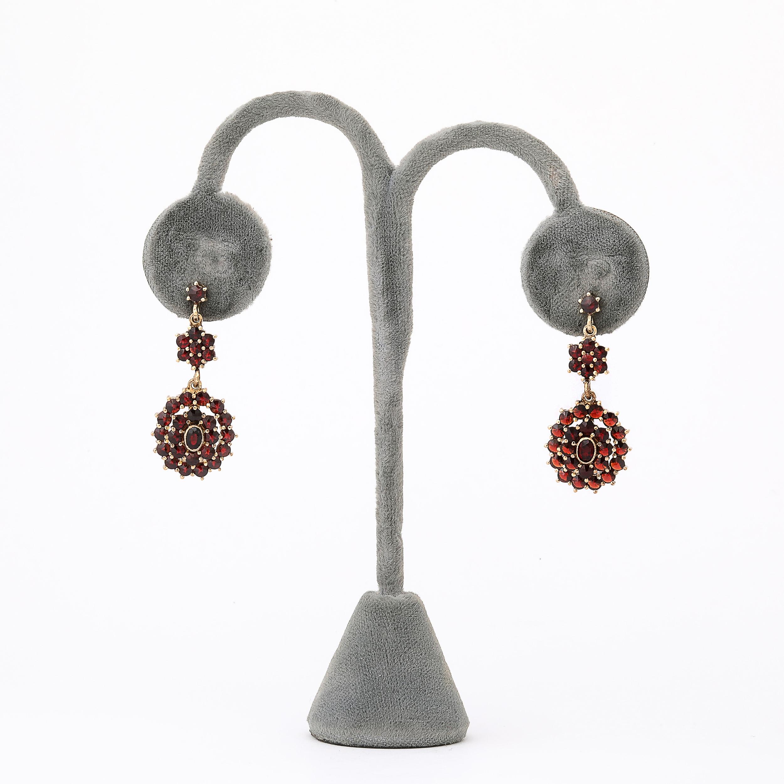 Cette exquise paire de boucles d'oreilles anciennes met en valeur l'exceptionnel savoir-faire du design bohémien de la fin du XIXe siècle, originaire de Tchécoslovaquie vers 1880. Les boucles d'oreilles sont ornées de grappes de grenats vifs et