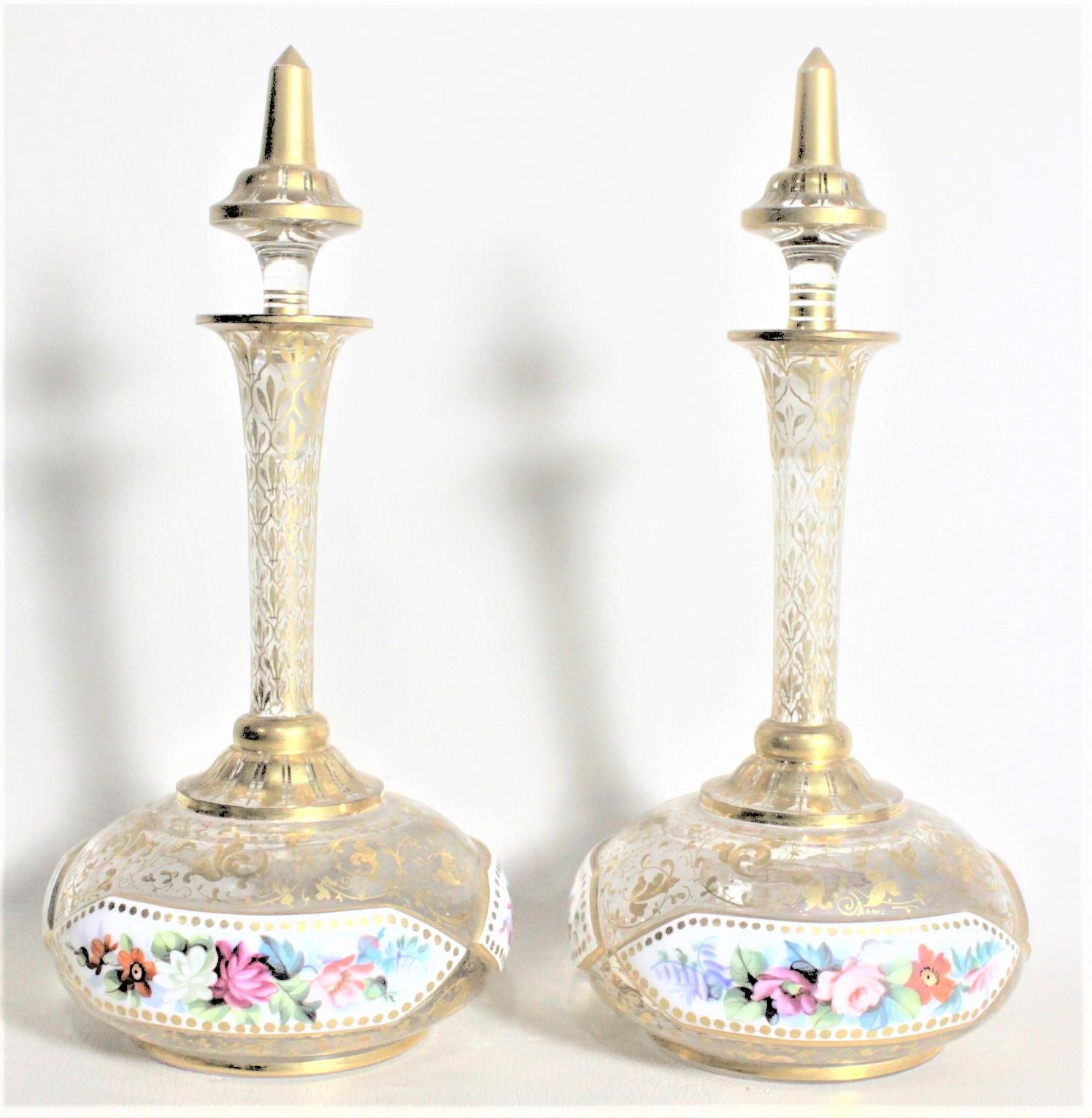 This pair of gilt and enameled glass perfume or scent bottles are unsigned, but presumed to have been made in Austria in circa 1925 in an Art Deco style. Each bottle from this matched set has three elongated enamel panels around the outside of their