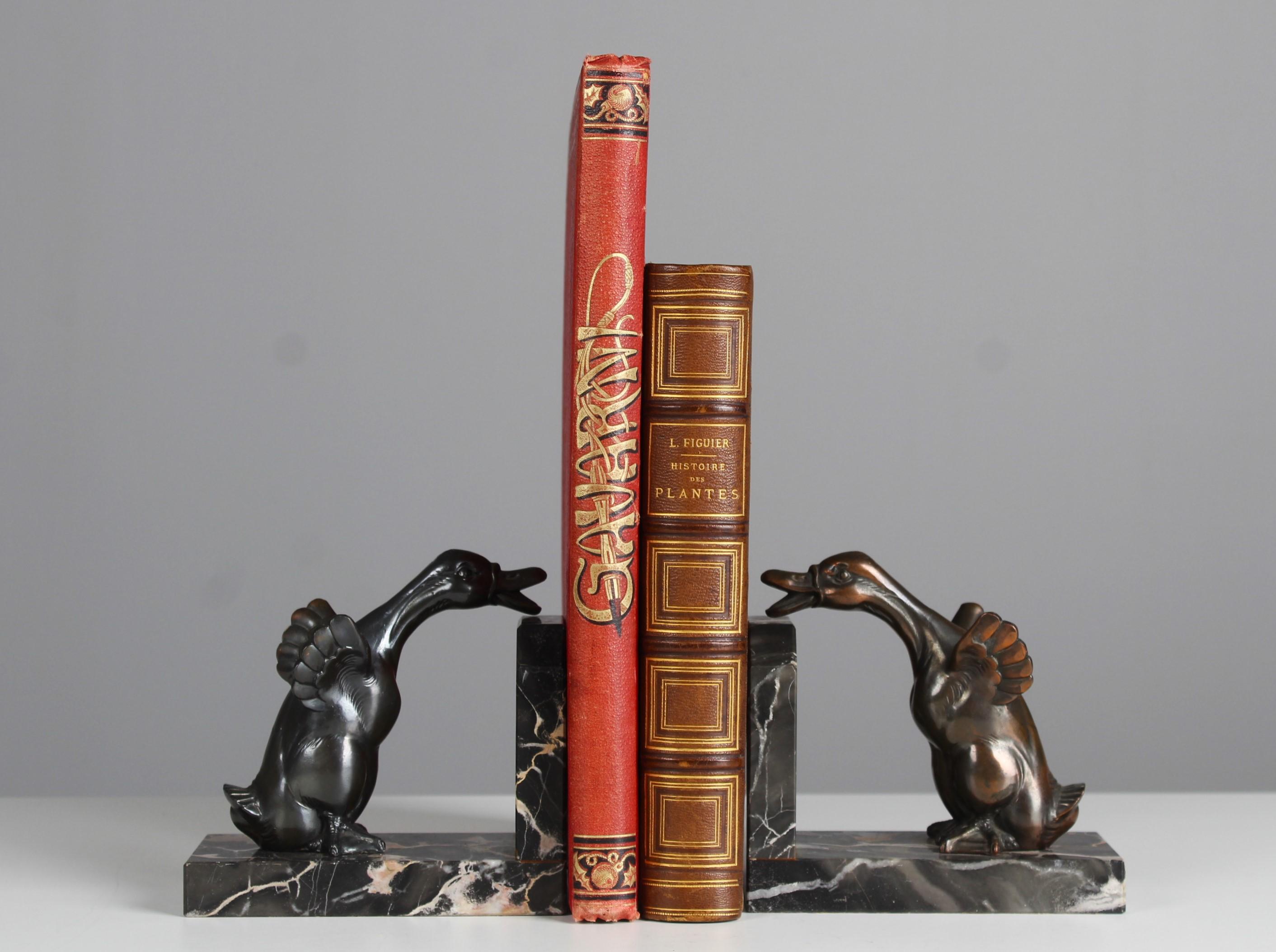 Schöne antike Buchstützen mit Skulpturen von zwei Gänsen auf einem Marmorsockel.
