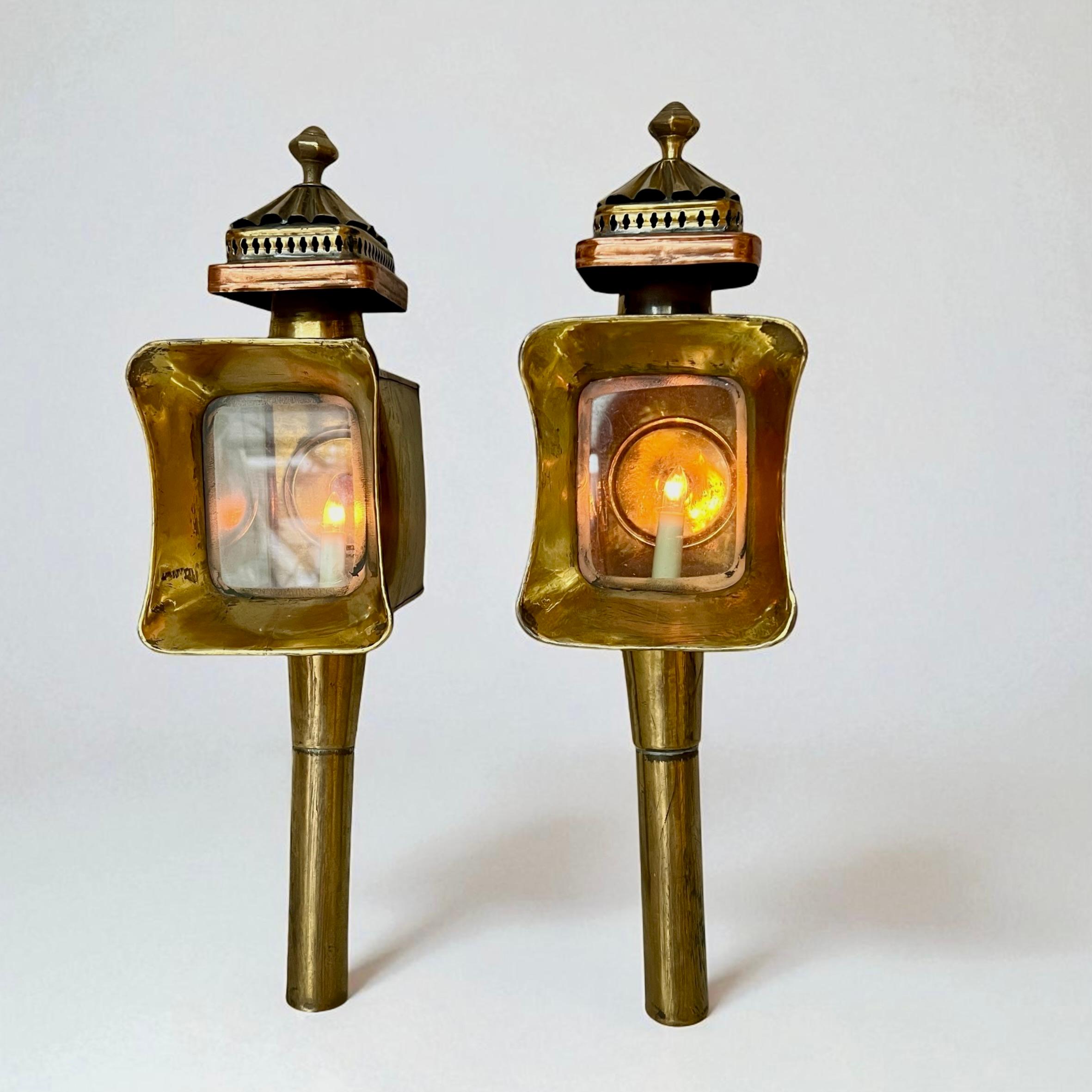 Este llamativo par de lámparas de carruaje antiguas presenta hermosas marquesinas perforadas con la parte superior entoldada, cada una coronada con un remate decorativo. Las cajas de luz están acristaladas por tres lados, con una ventana frontal