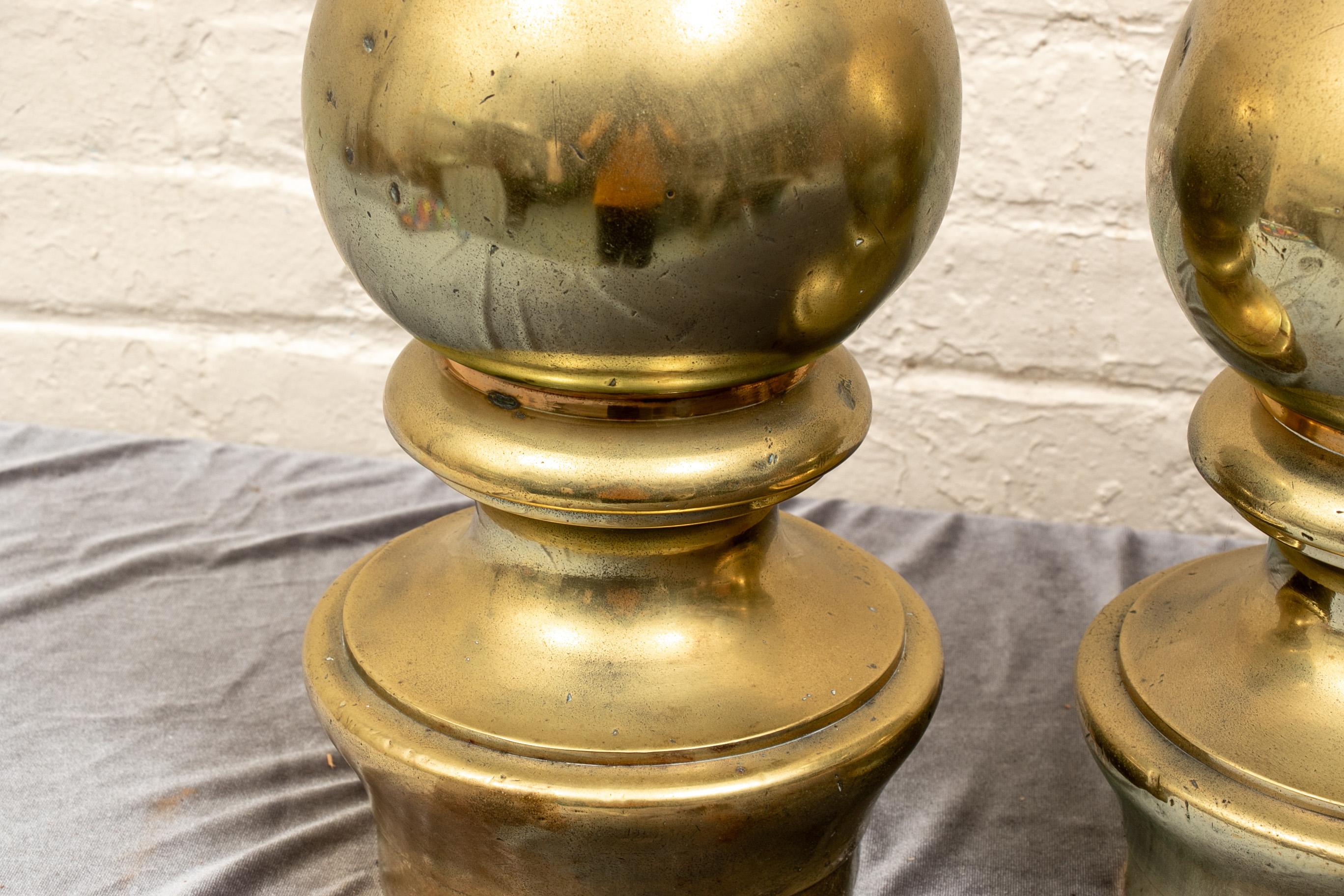 Pair of antique brass bollards. A spherical top over a short turned standard and raised on a circular stepped base. Drill holes along base allowing to be affixed to boat deck. 

Condition: Good condition with expected signs of use, some sporadic