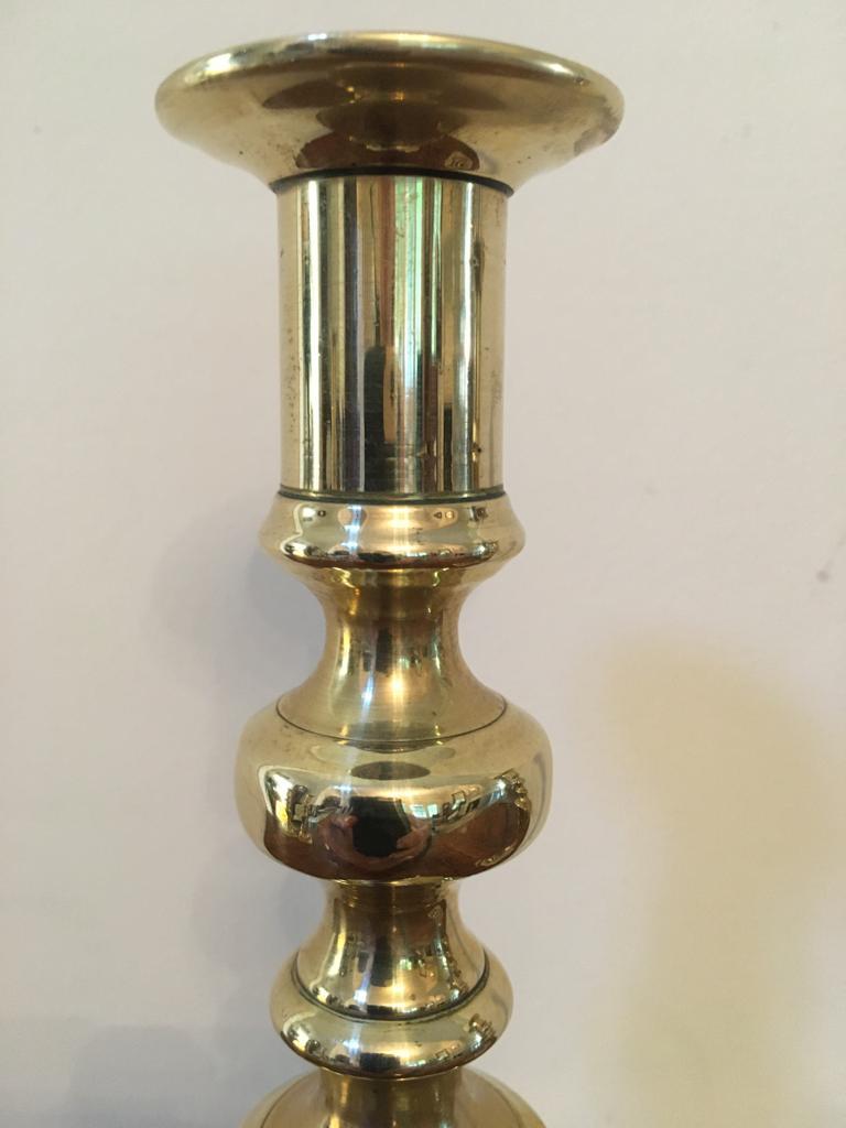 Pair of antique brass candlesticks with a shaped column, rising from a shaped stepped base, each candlestick retains its original push ejector rod.
   
